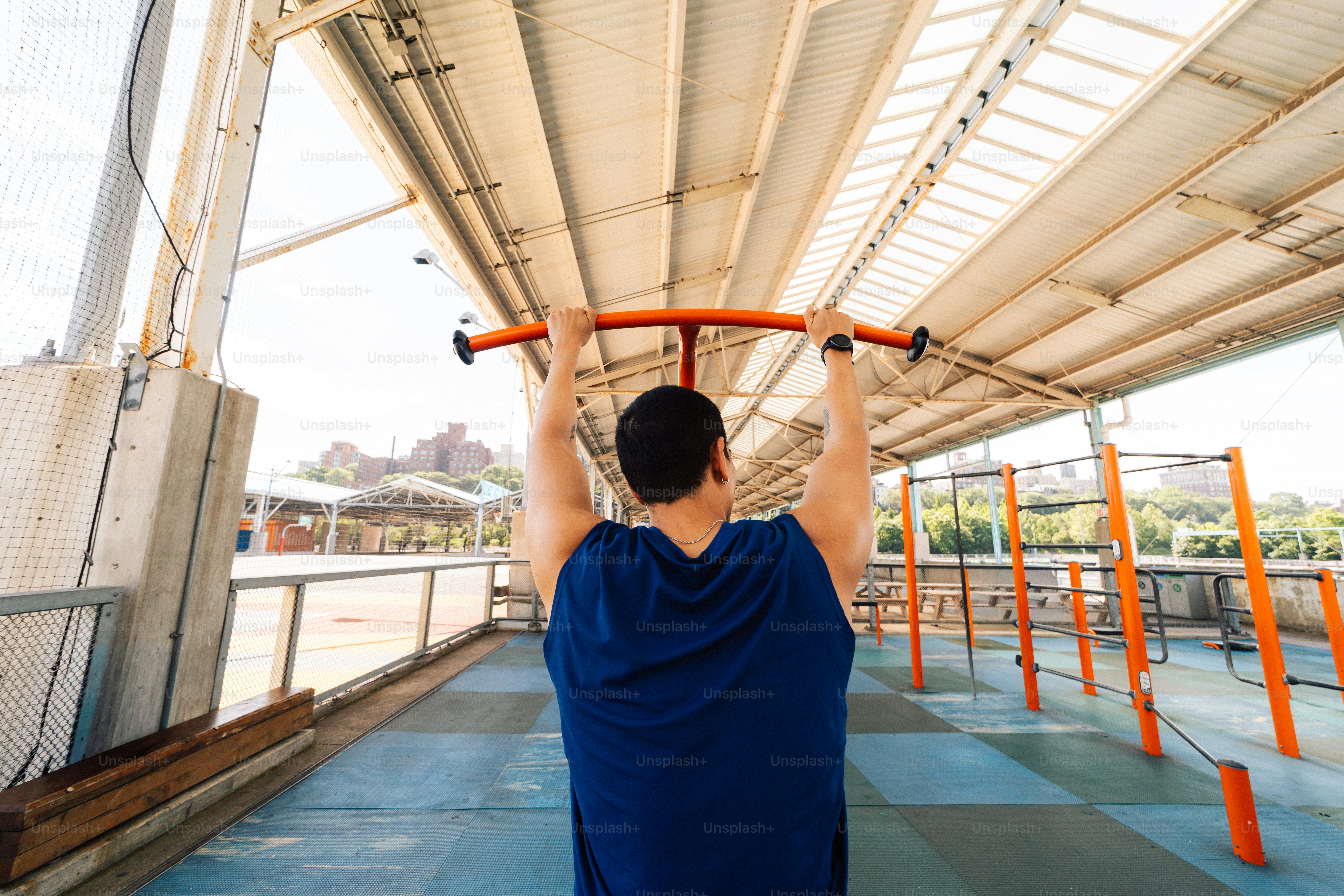 Pria berolahraga di pull-up bar di luar ruangan.
