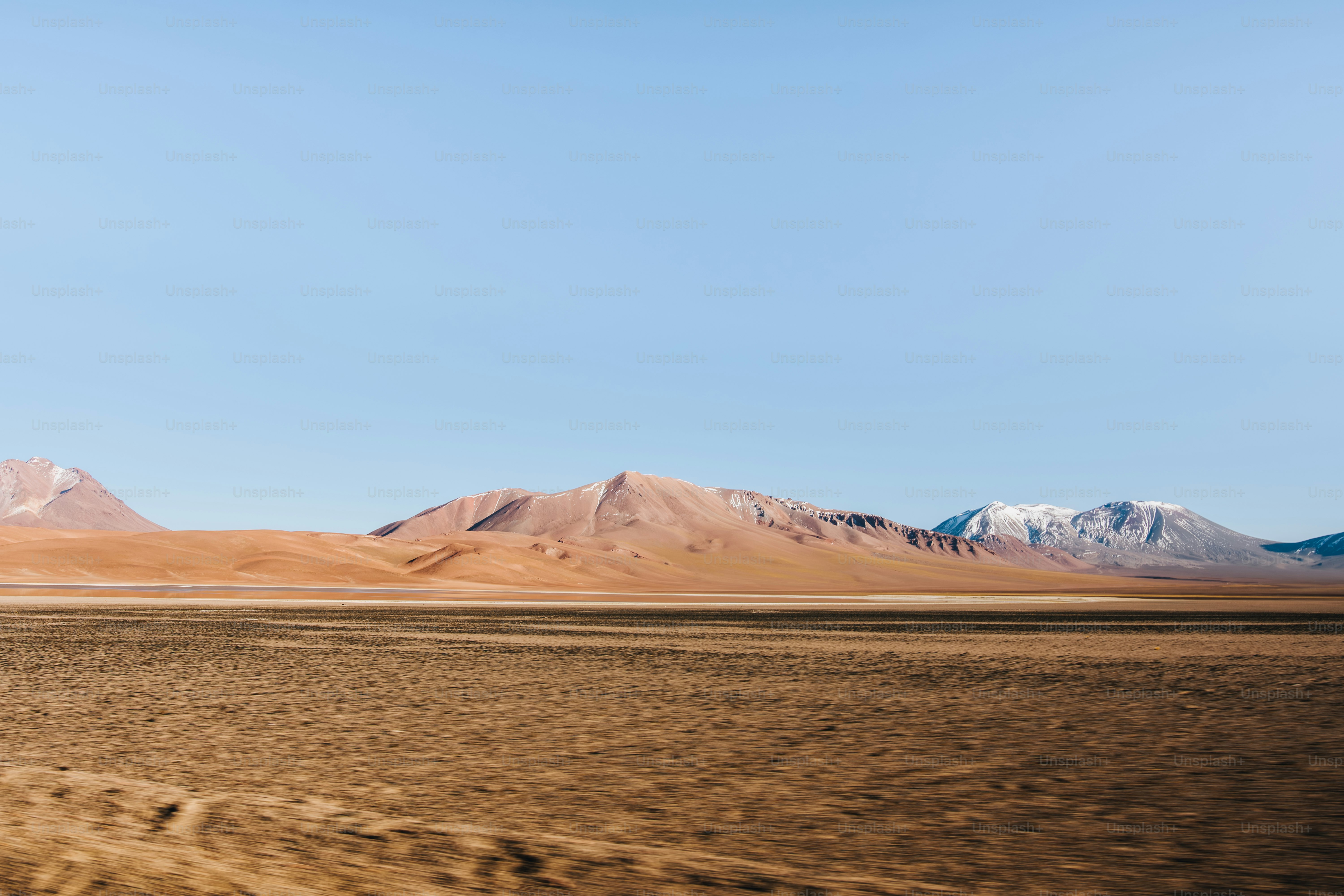Vast desert landscape with mountains under a clear blue sky