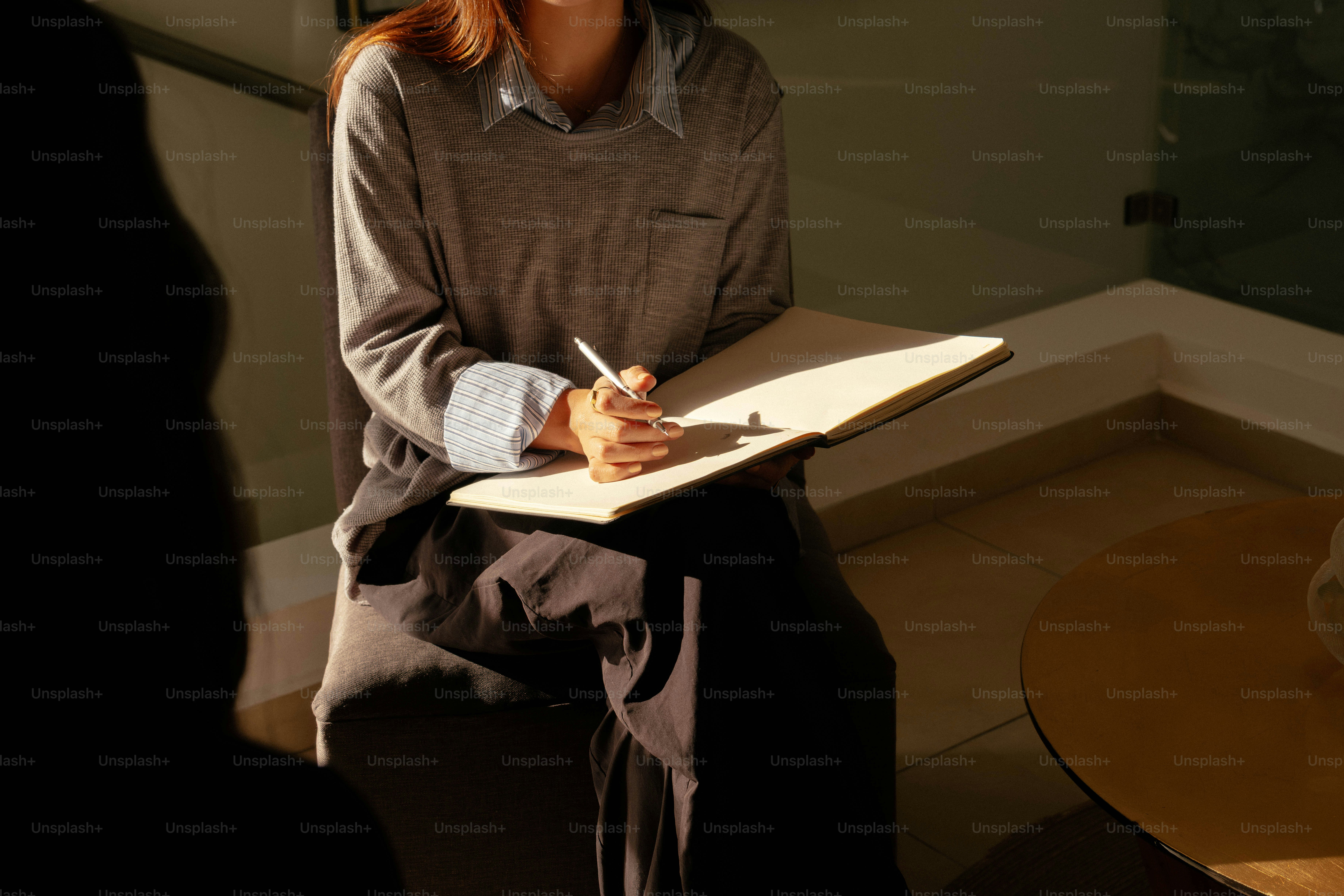 Mulher escrevendo em um caderno durante uma conversa.
