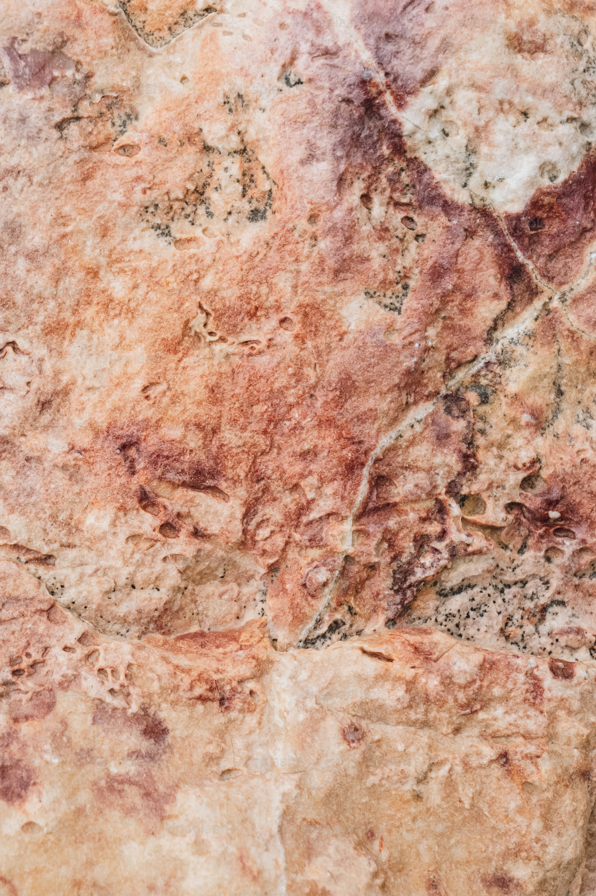 Rough, textured surface of reddish-brown and white rock.