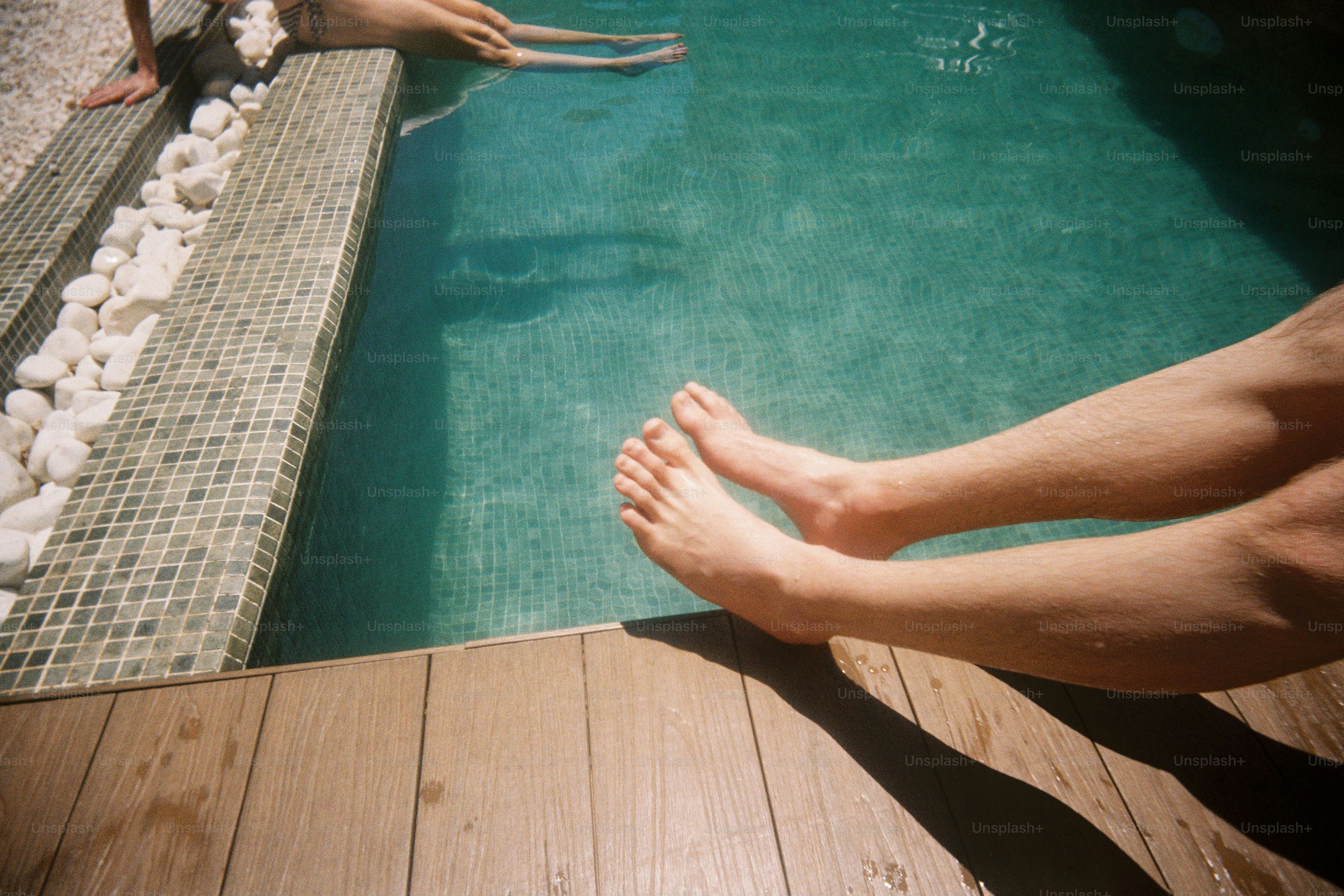 Pés pendurados sobre uma piscina turquesa.