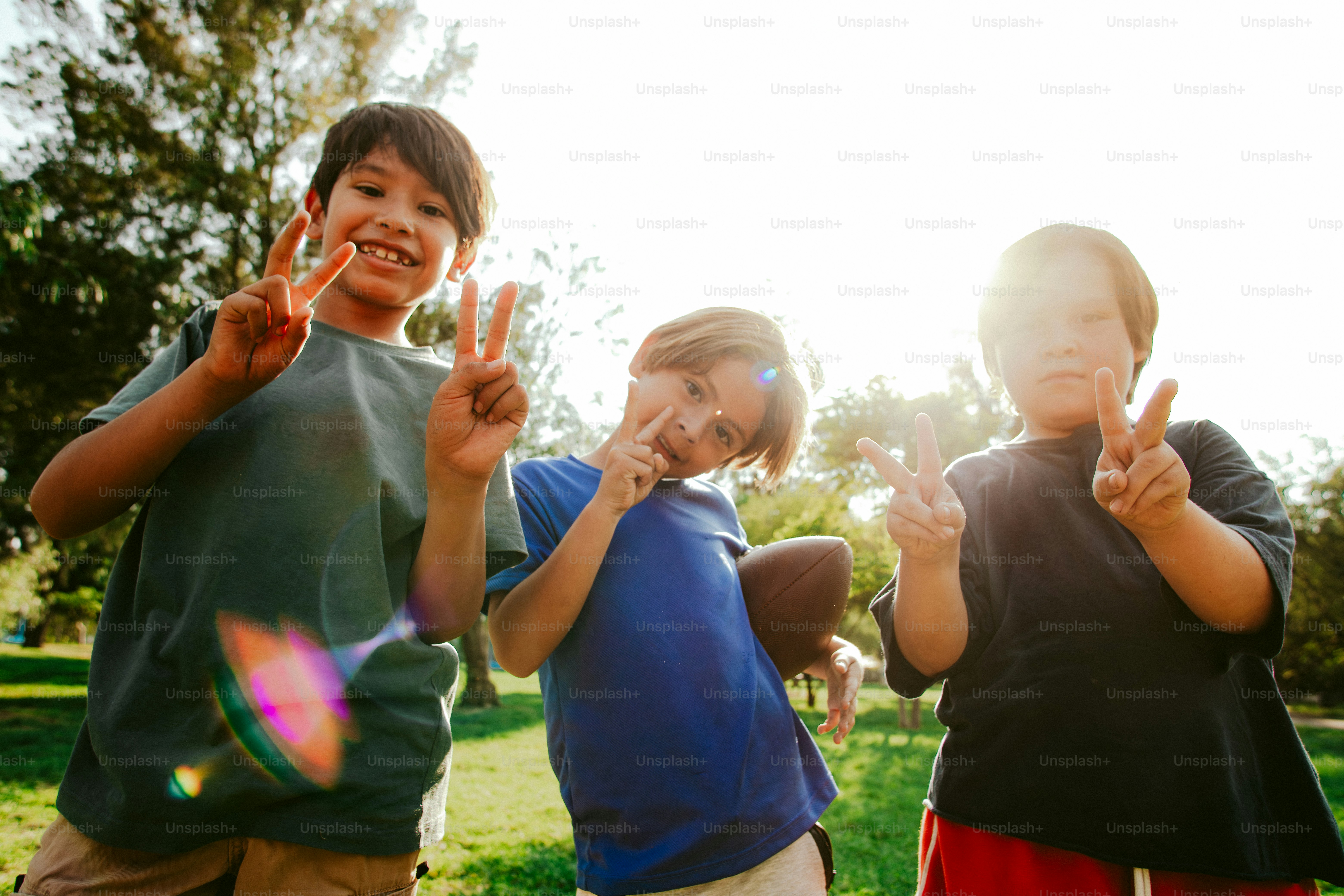 Boys making peace signs in sunny park