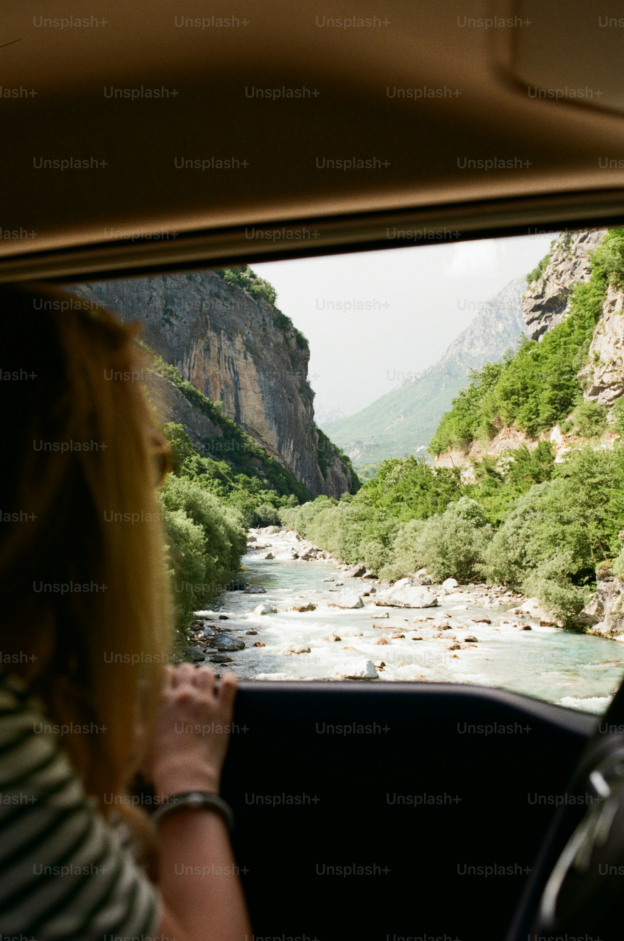 Woman looking at mountain river from car window