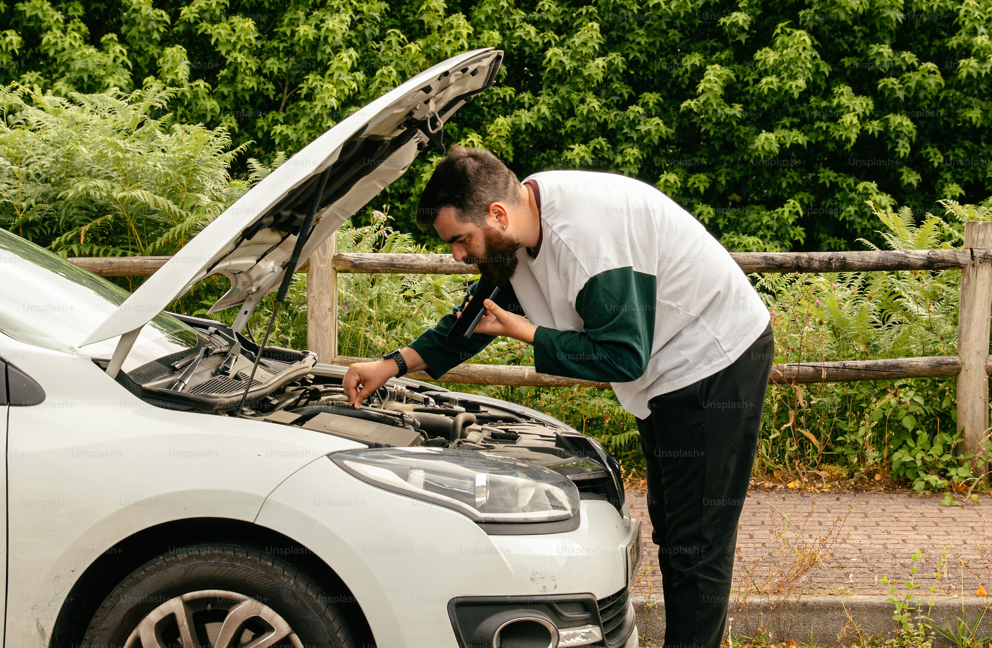 Man examining car engine under open hood