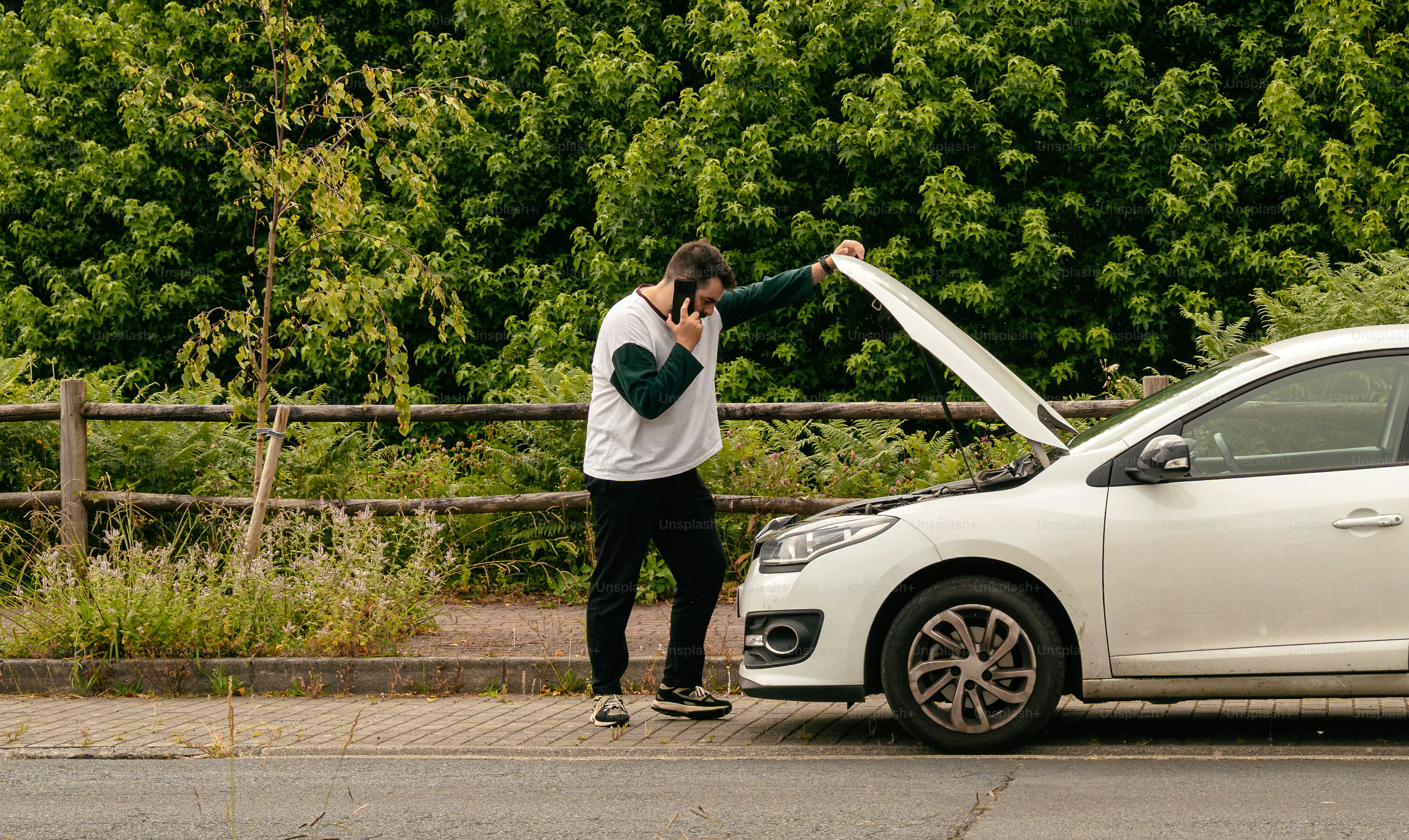 Man talking on phone by broken down car