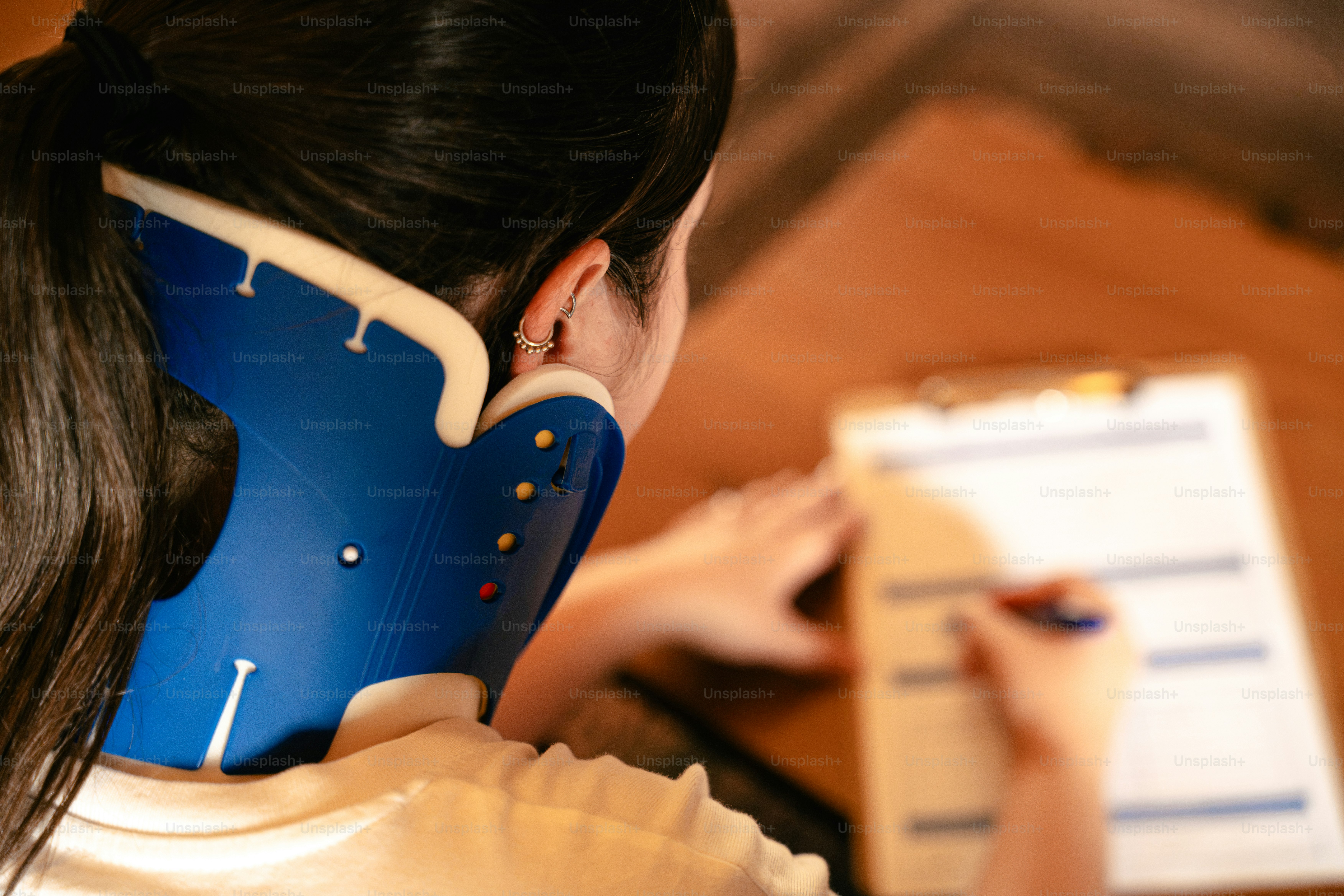 Woman wearing neck brace writing on clipboard