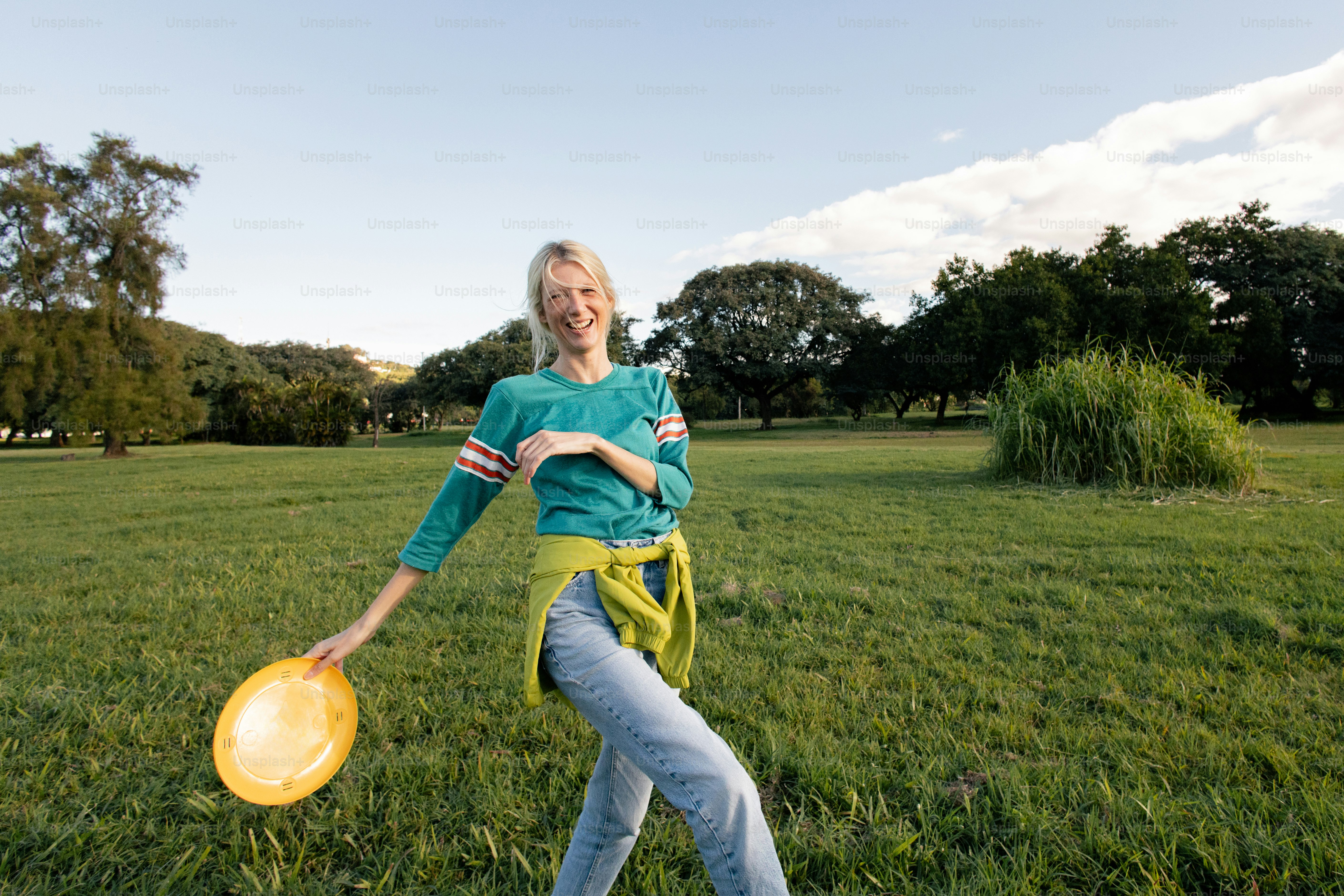 Smiling woman in park holding a yellow frisbee