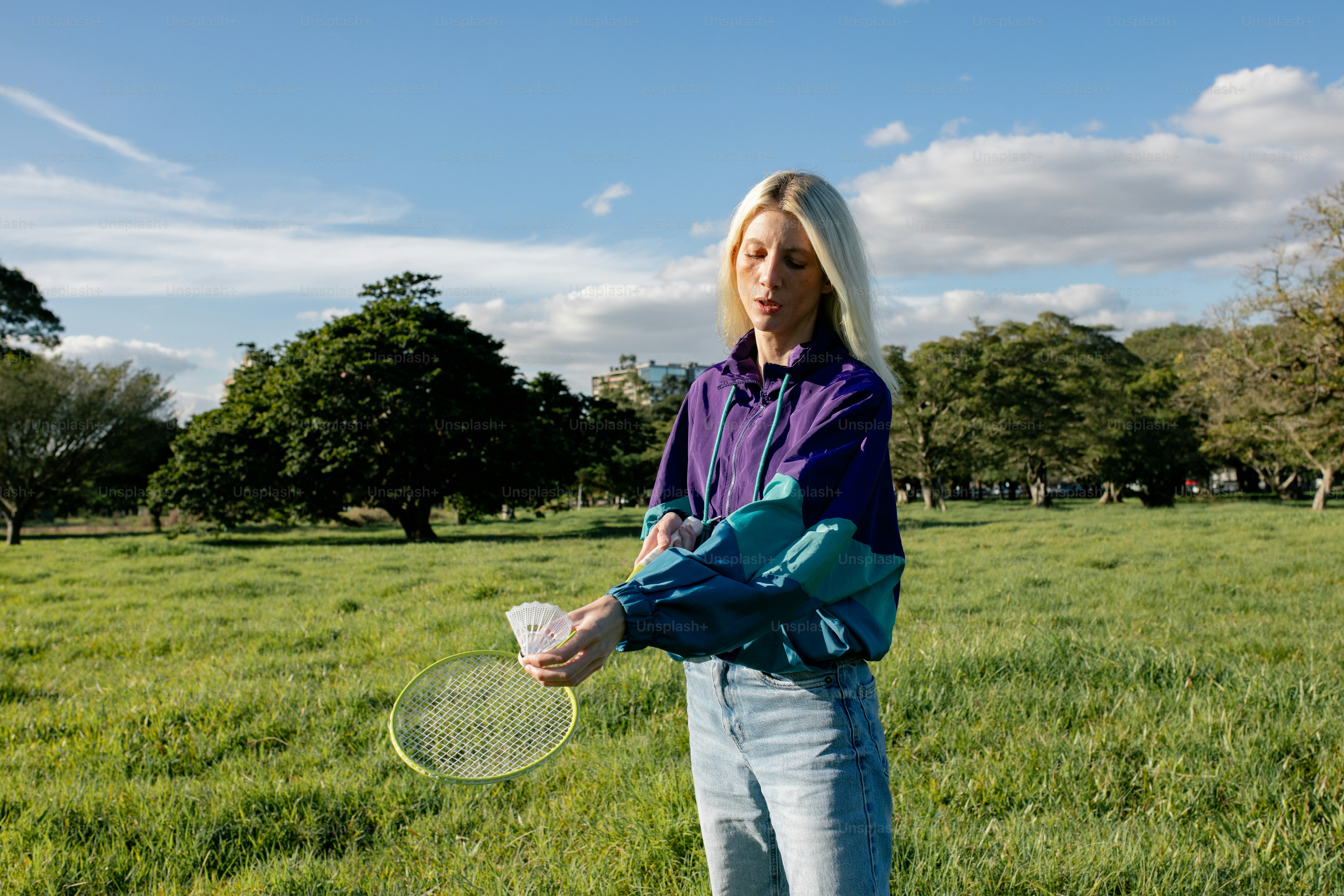 Woman in windbreaker blowing bubbles in sunny park