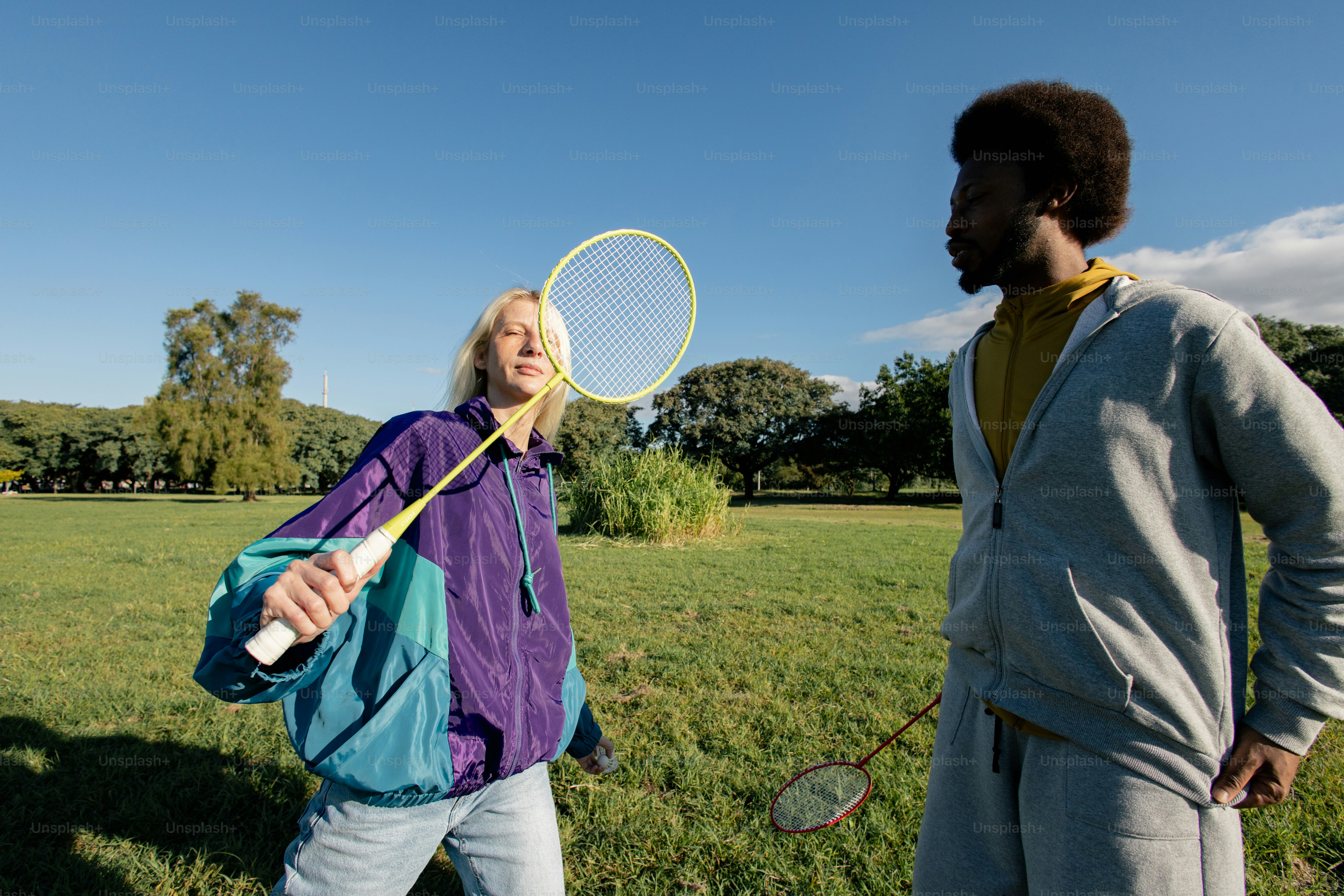 Two people playing badminton in a park