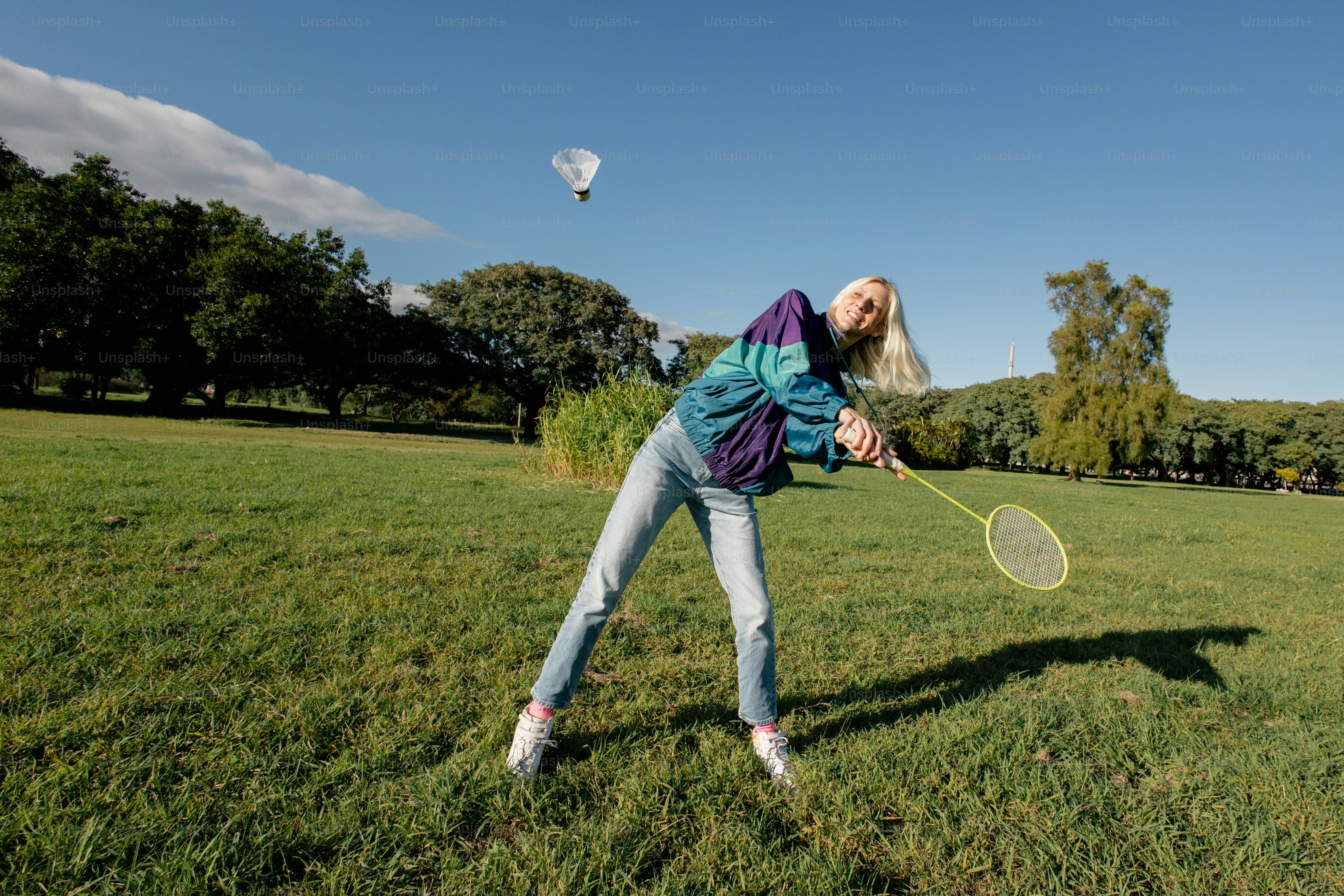 Badminton player in field, hot air balloon in sky