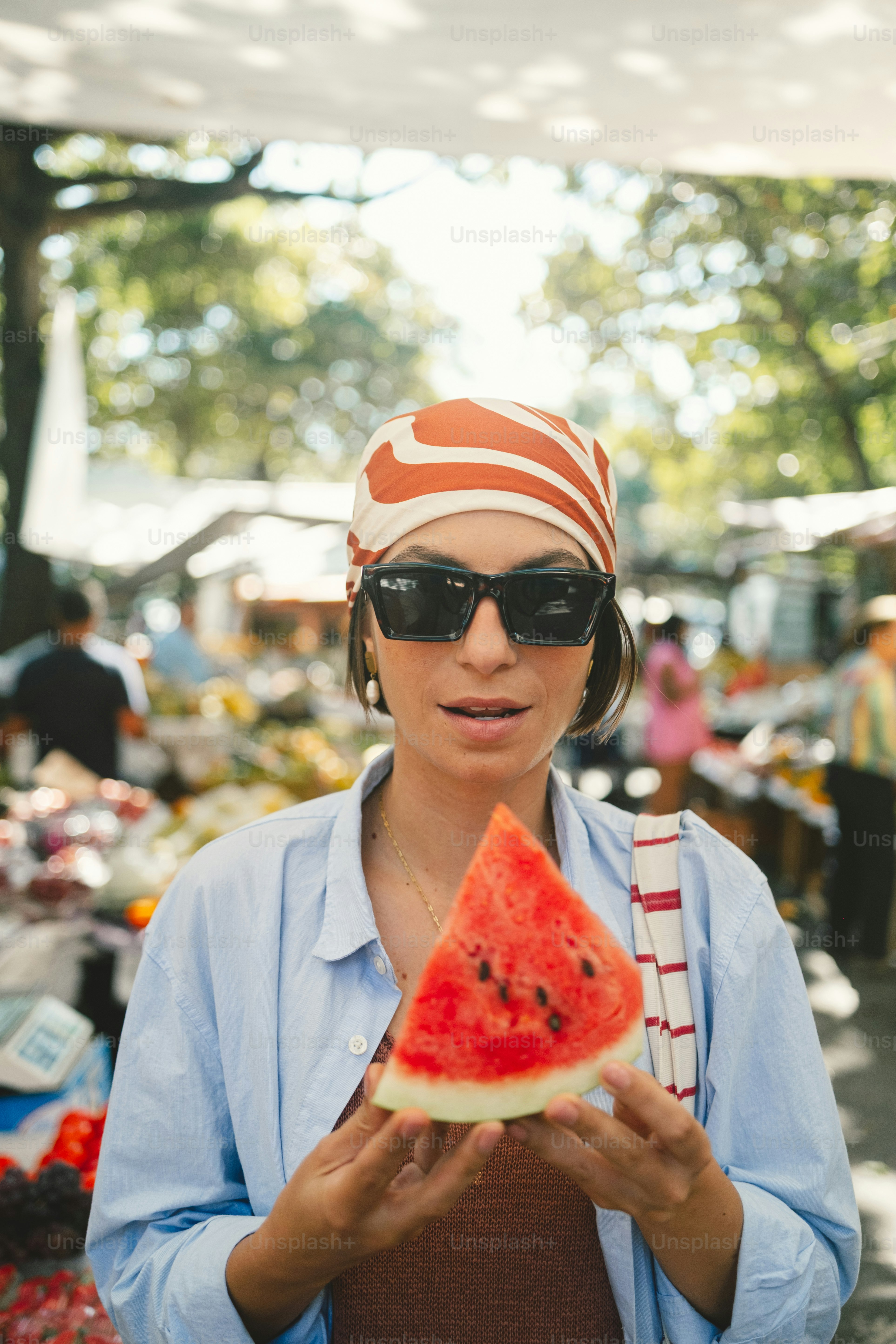 Woman holding watermelon slice at an outdoor market