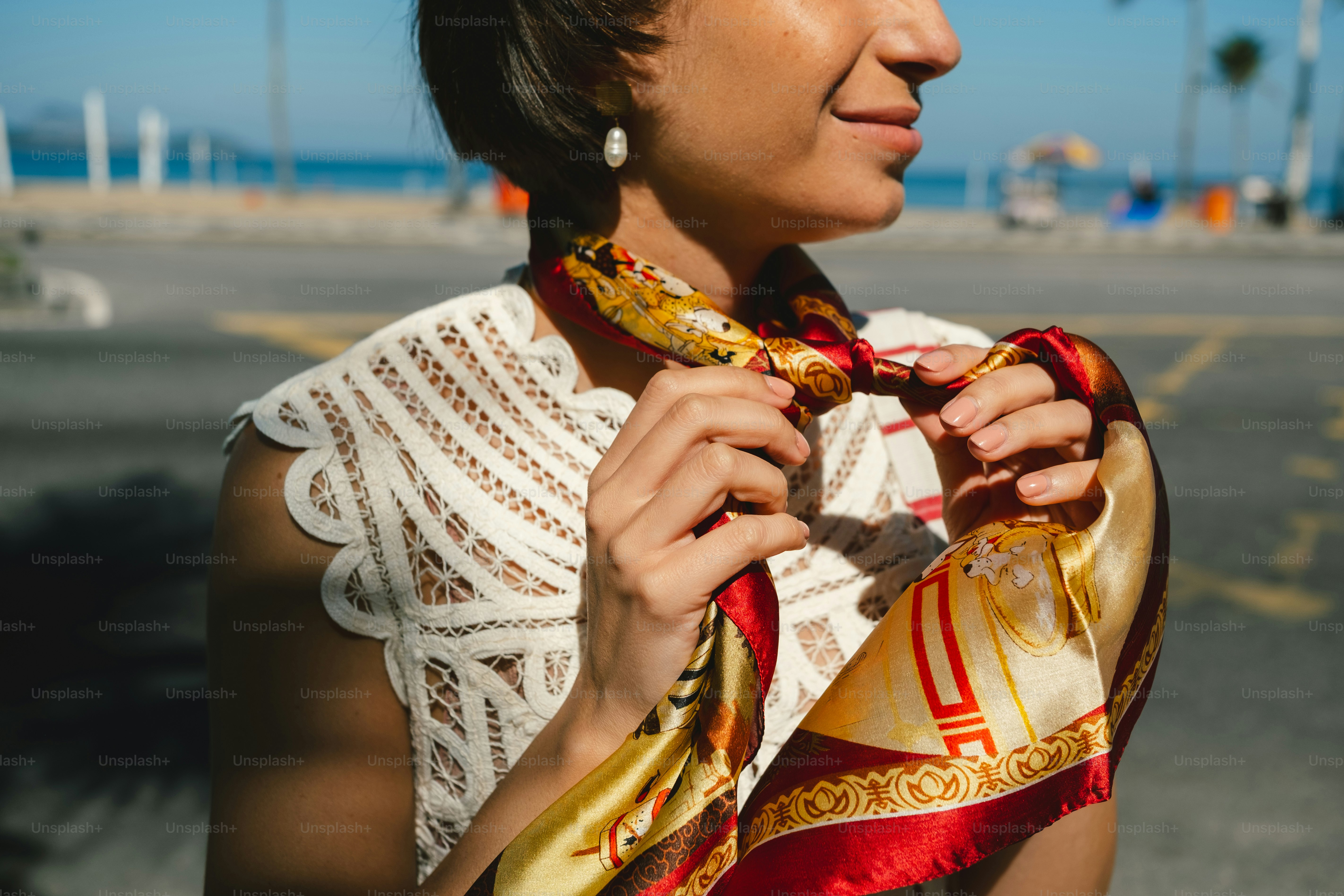 Woman tying colorful scarf, white lace top