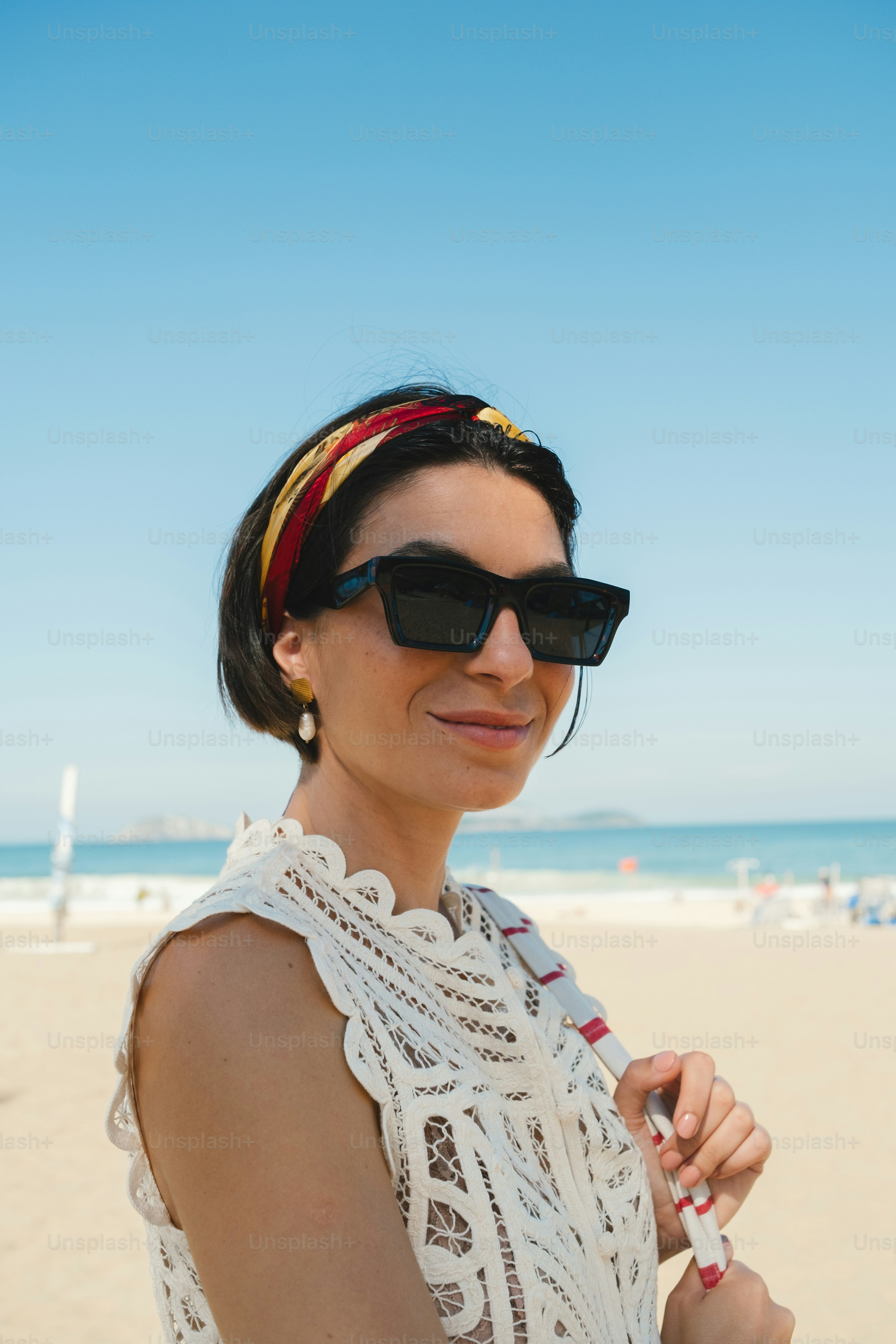 Smiling woman in sunglasses and lace top on beach