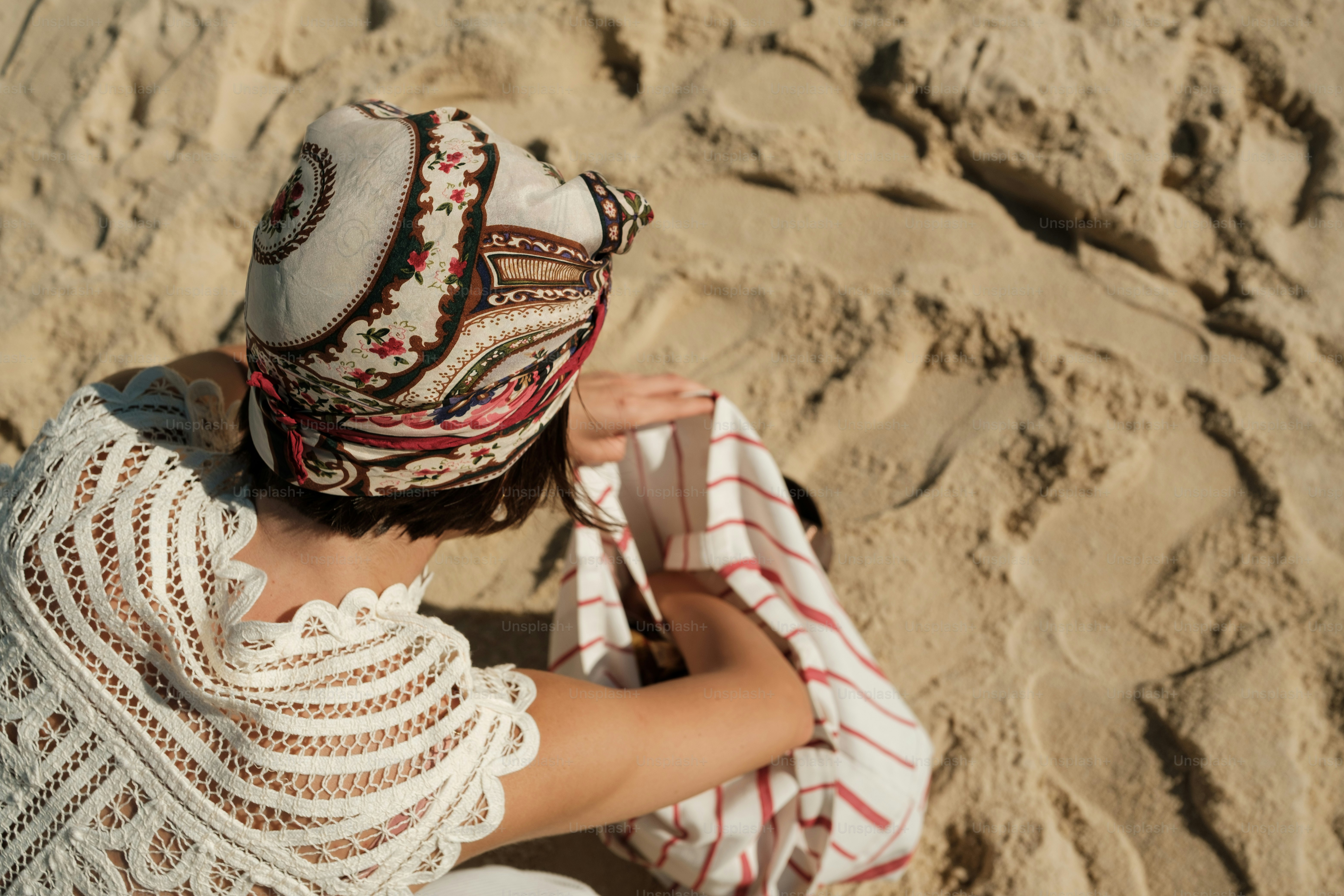 Woman in patterned headscarf interacting with sand