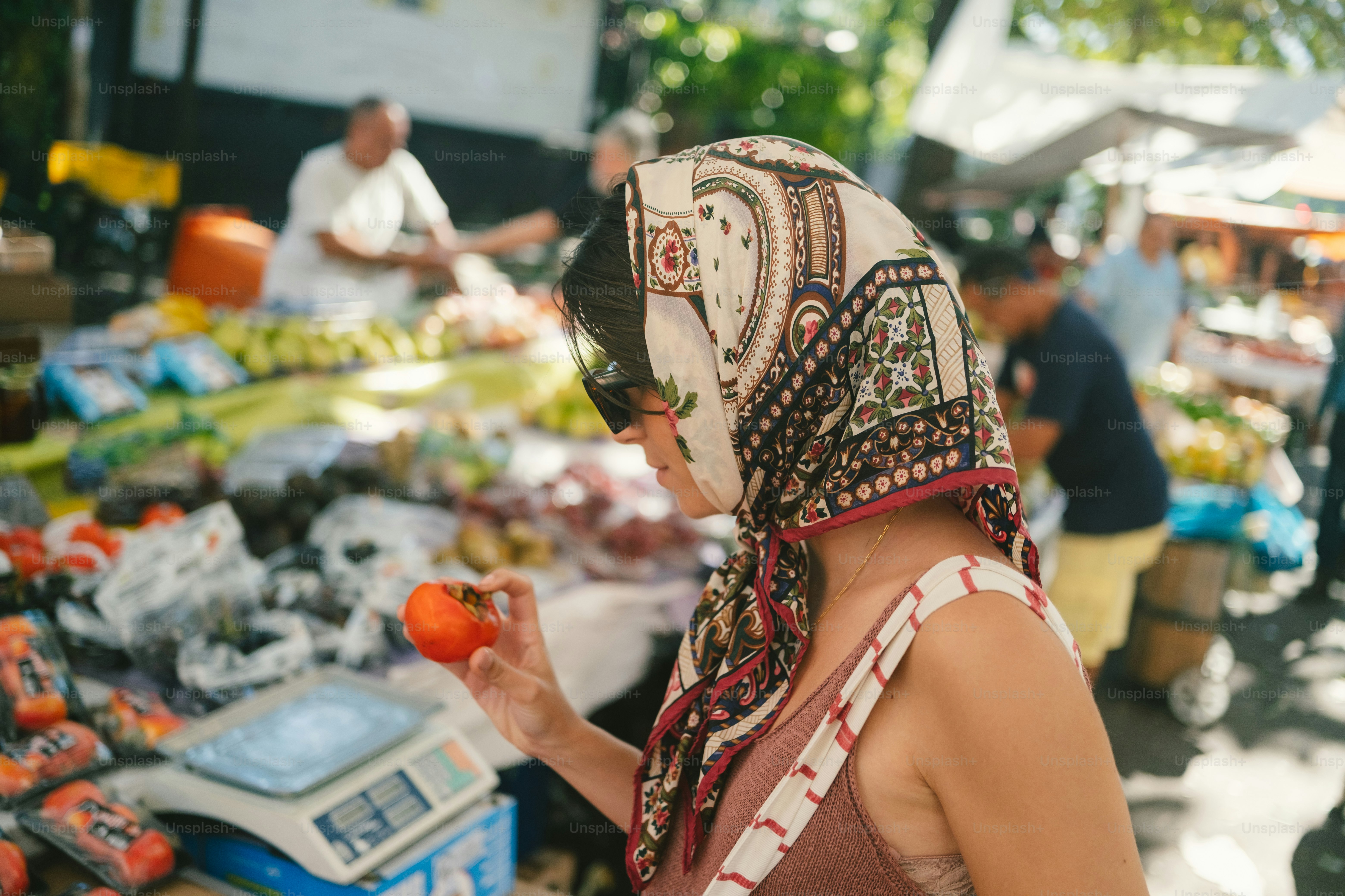 Woman in headscarf selecting fresh produce at market