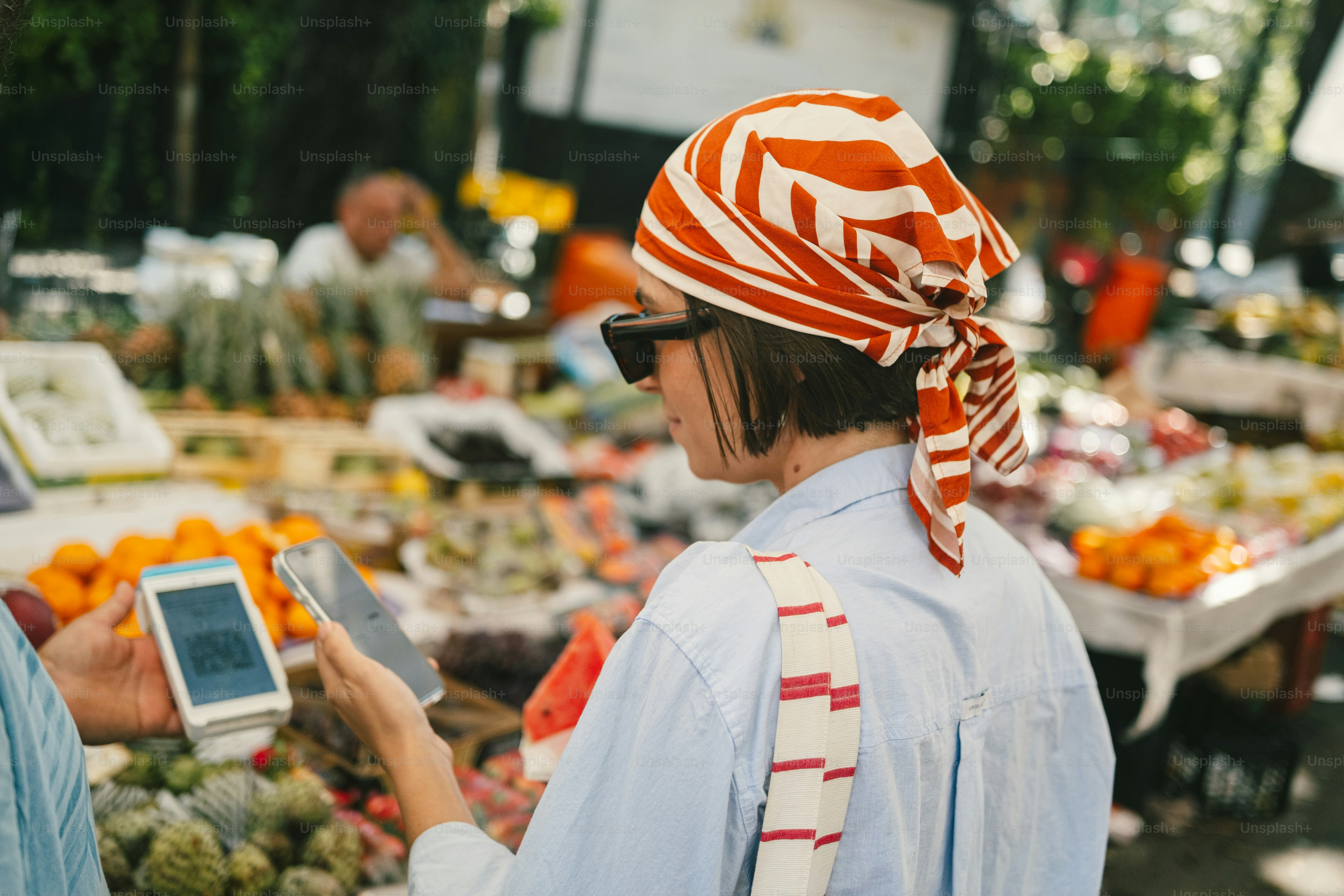Woman paying with smartphone at fruit market