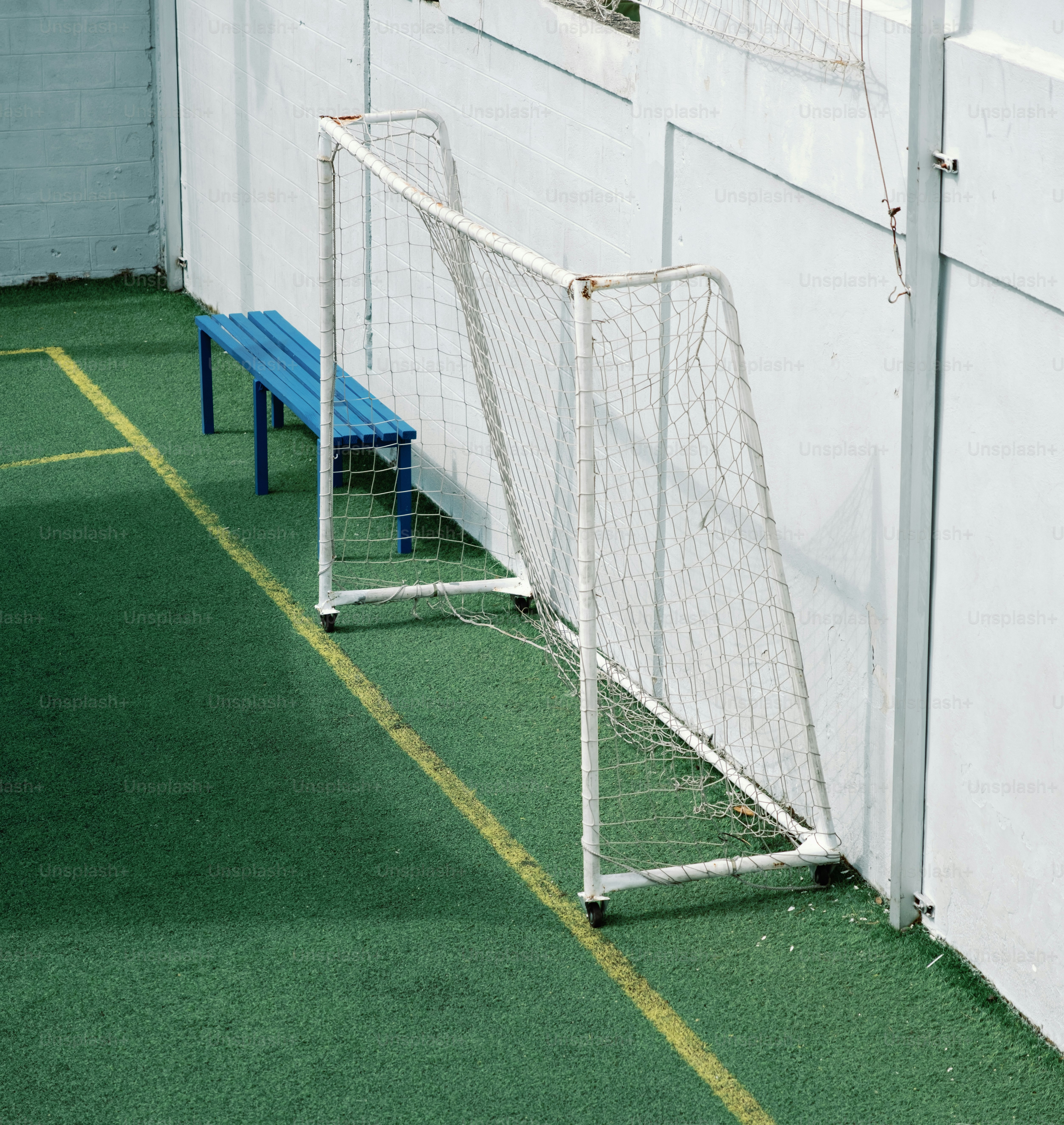 Gol de futebol e banco azul em grama verde