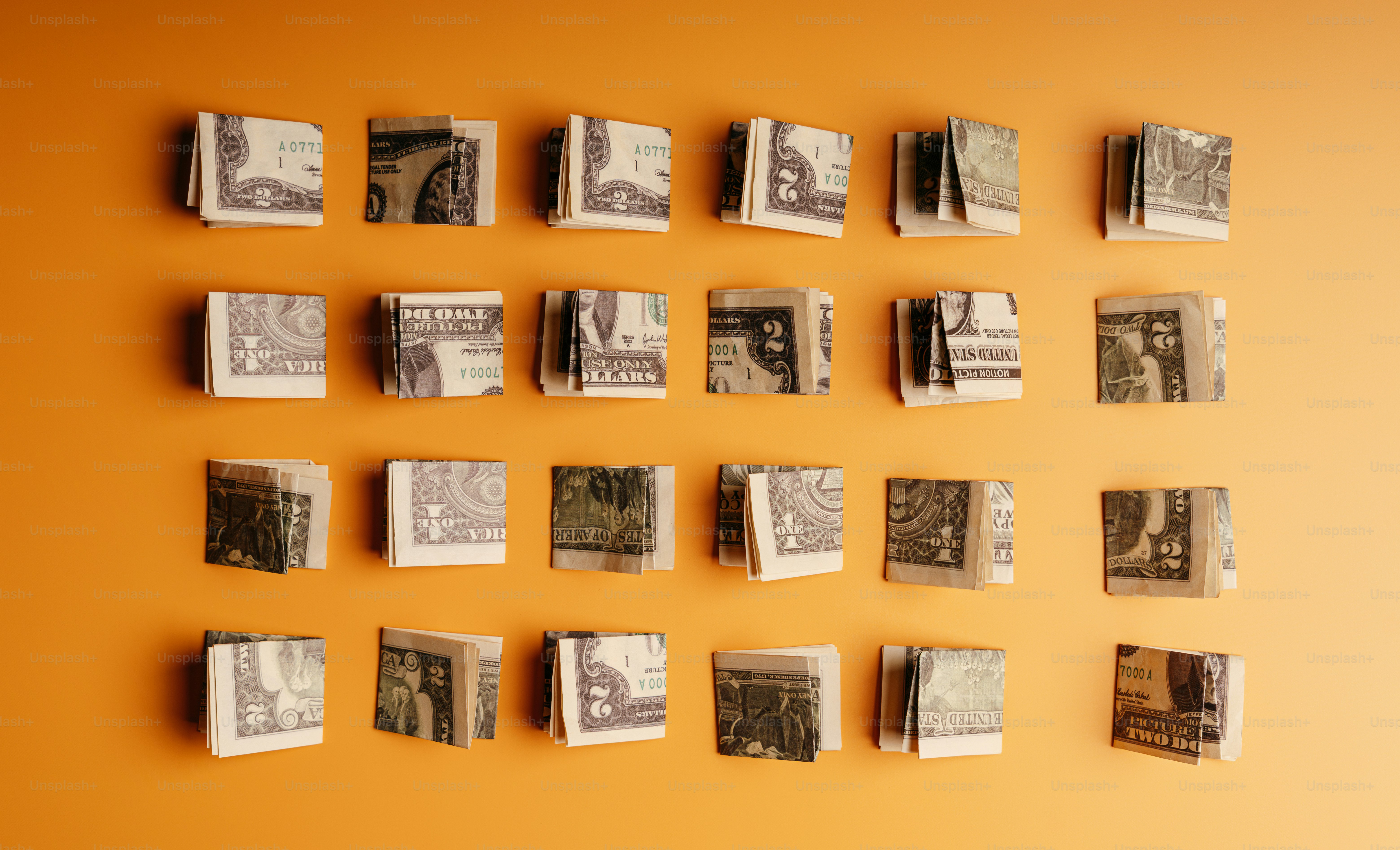 Folded currency stacks in a grid on orange photo – Finance Image on ...