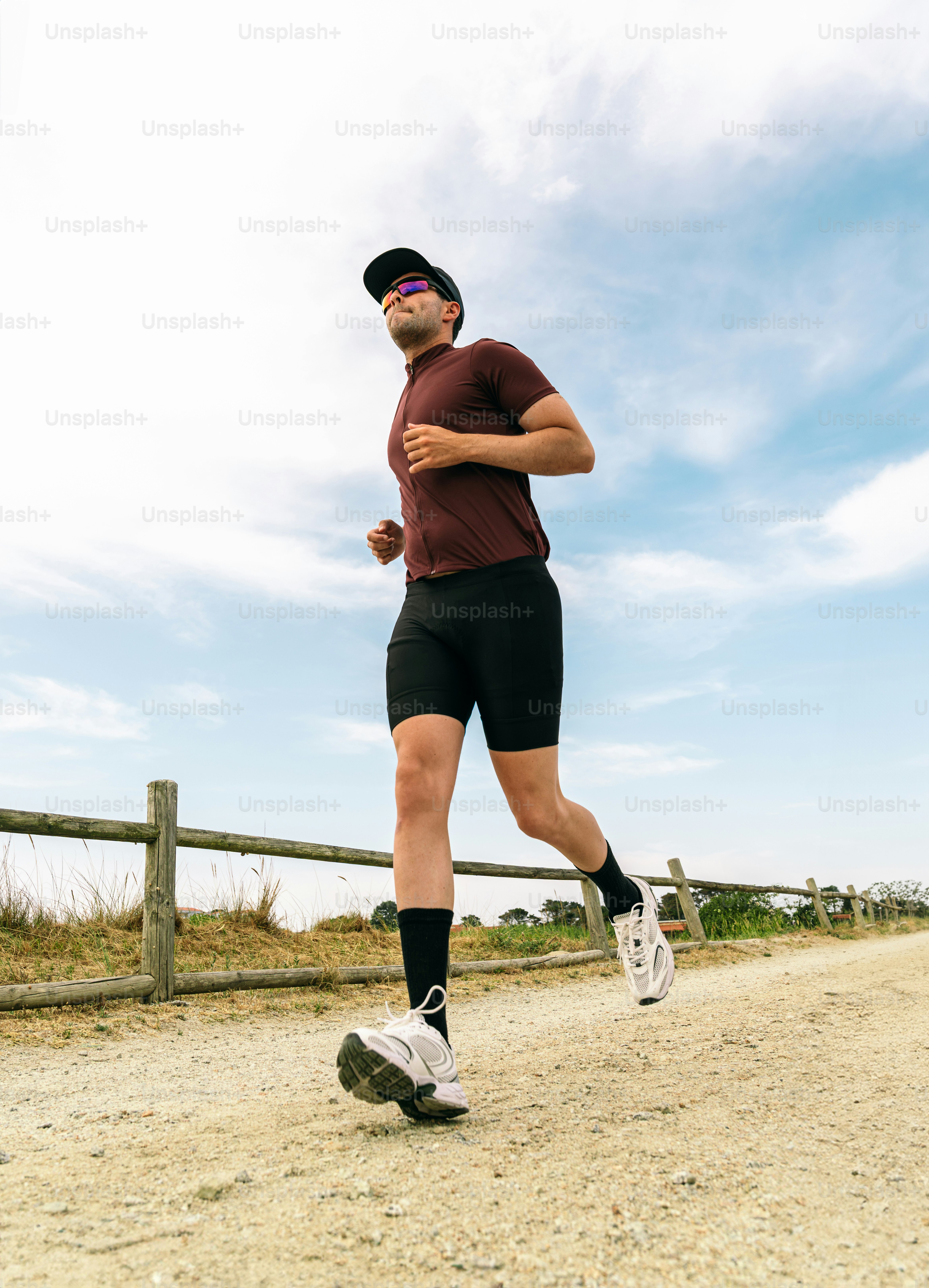 Man running on dirt path under blue sky
