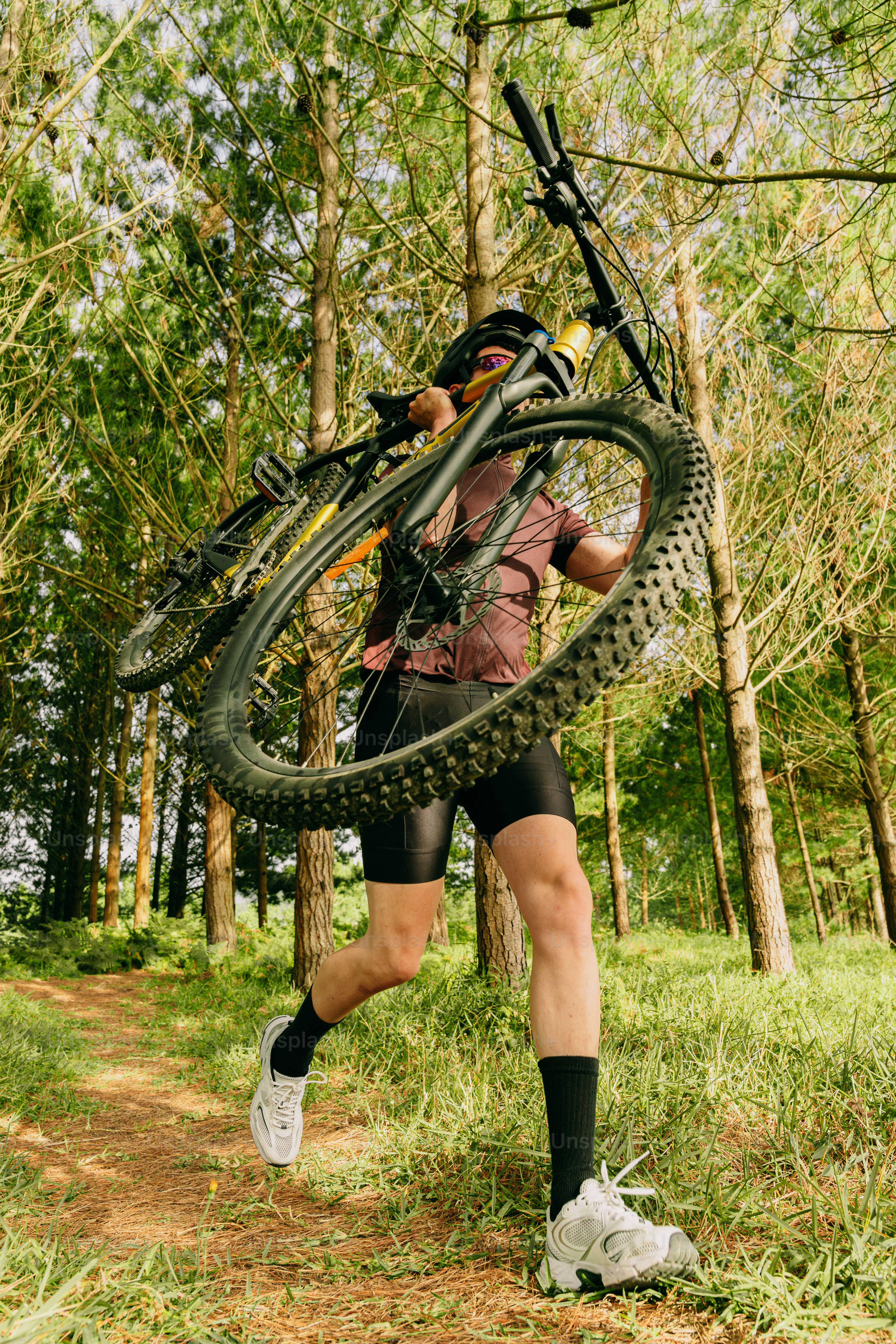 Mountain biker running with bike on forest trail