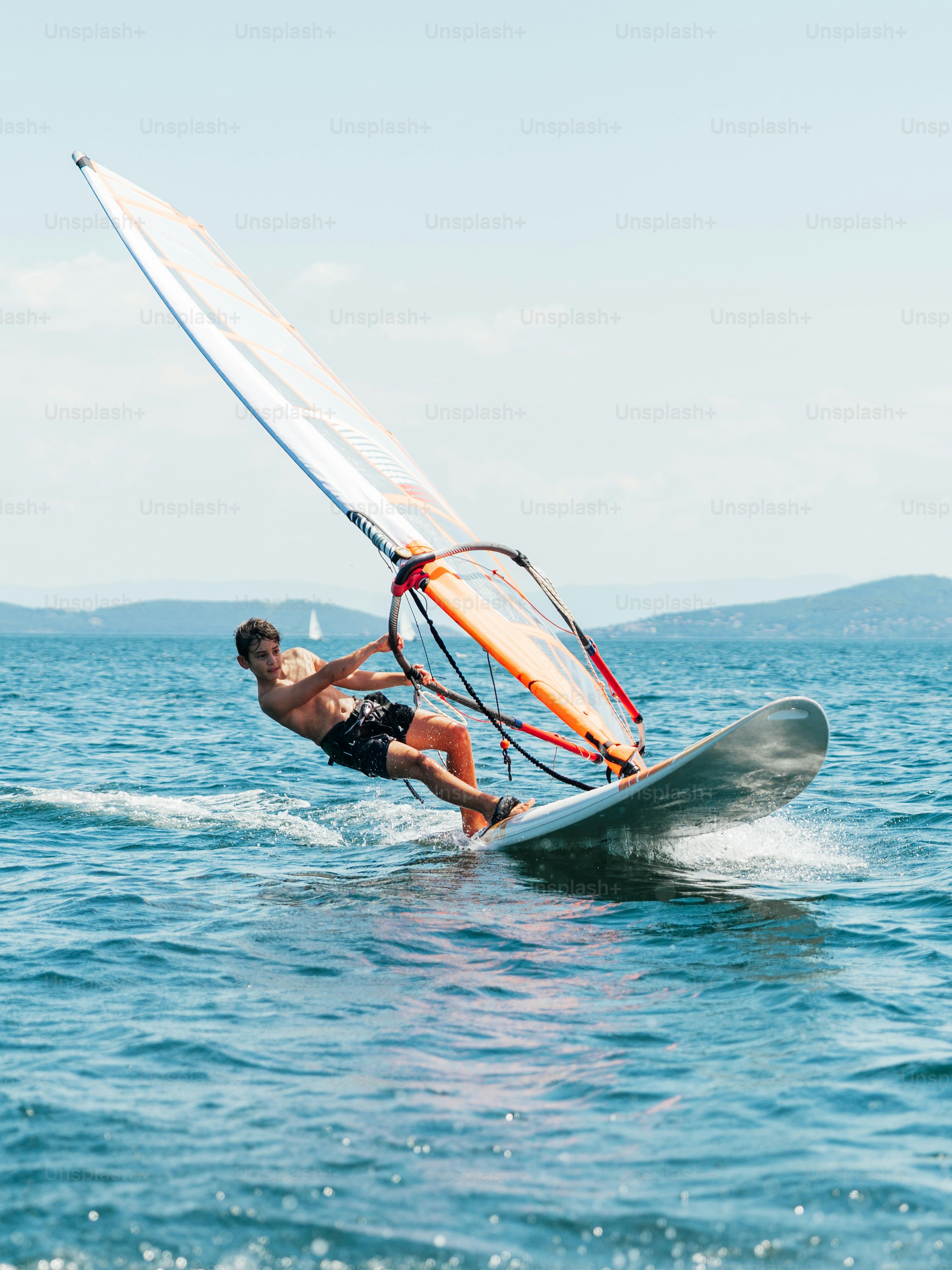 Man windsurfing on blue water under clear sky