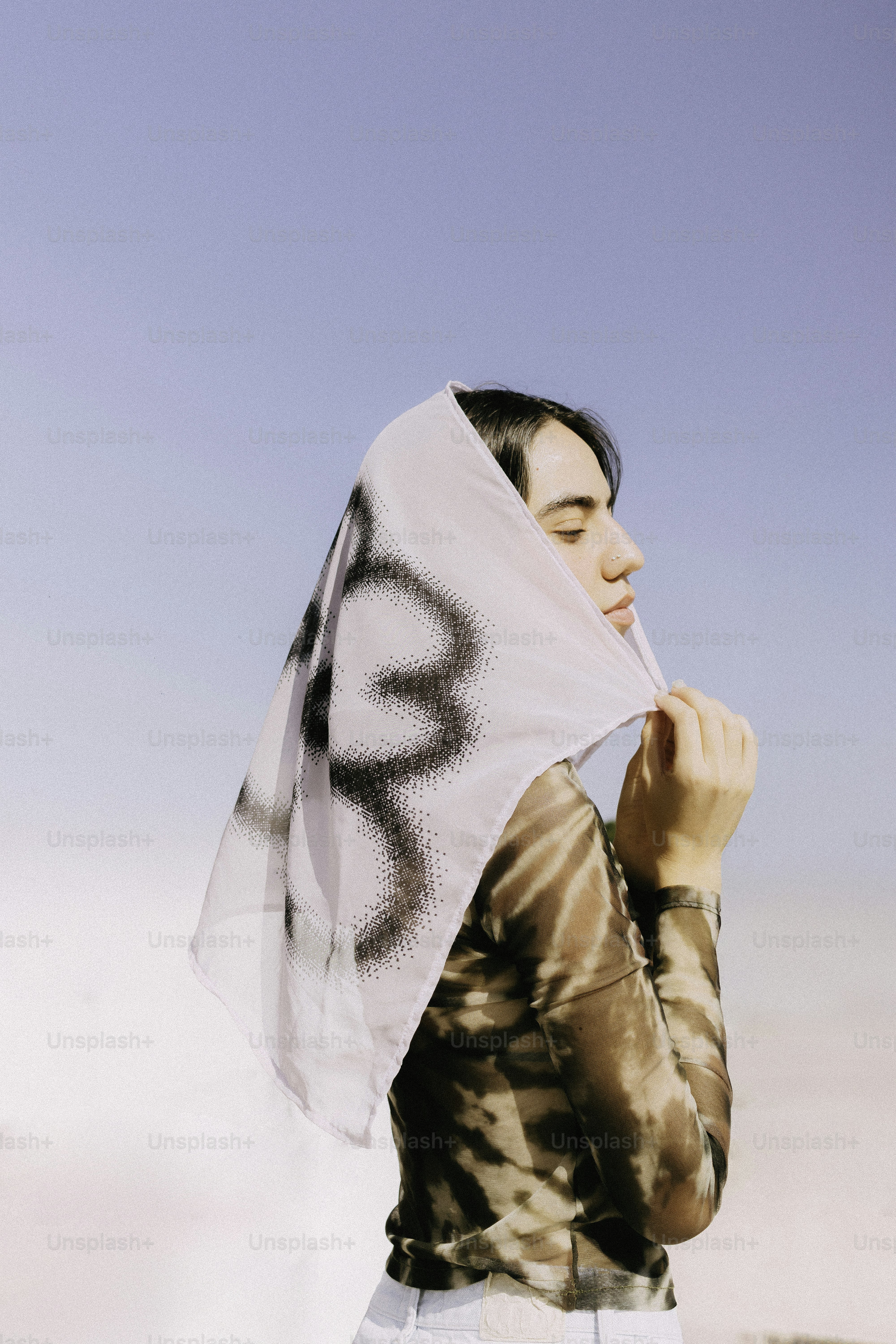 Person wearing patterned headscarf under clear blue sky