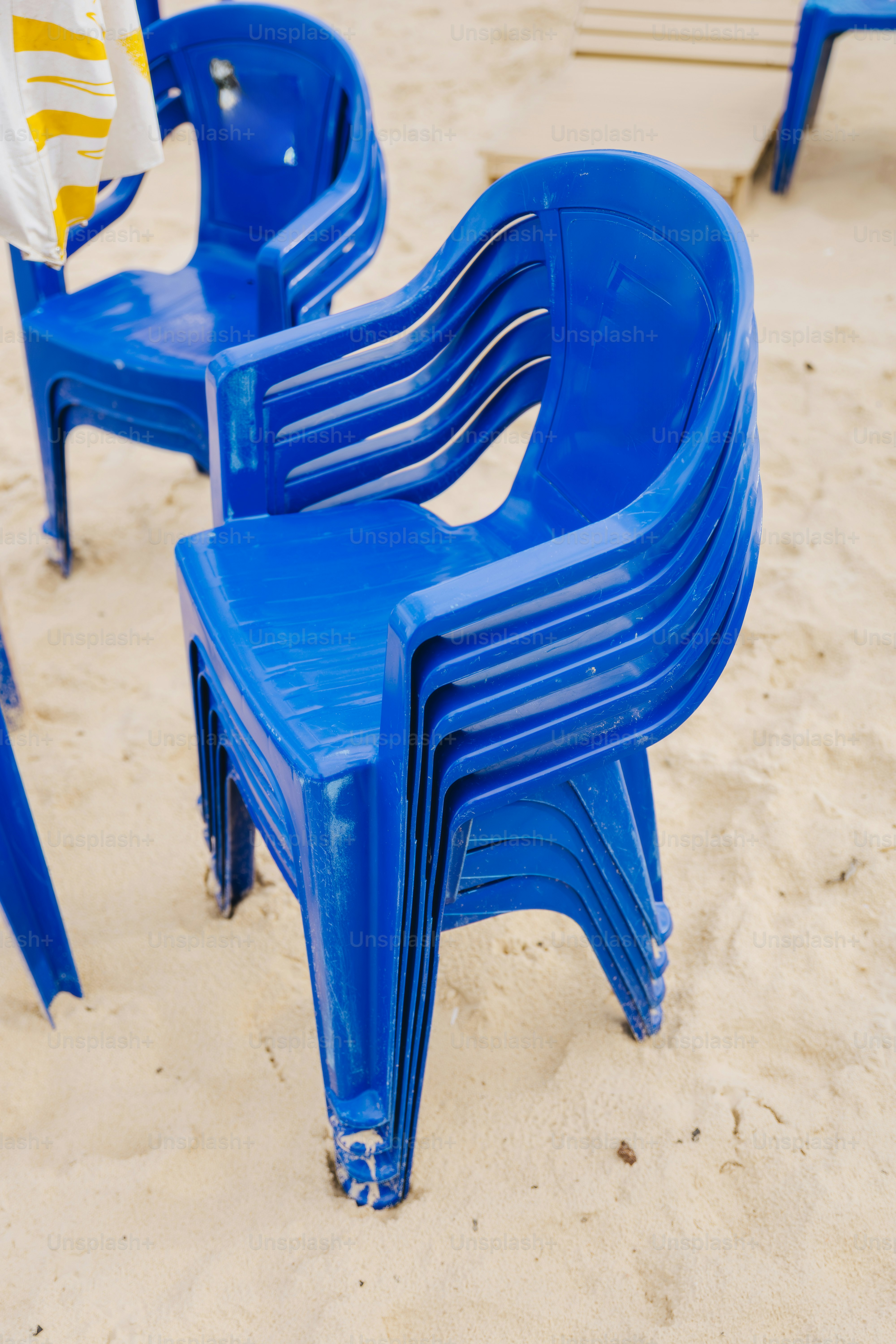 Stapel blauer Plastikstühle an einem Sandstrand