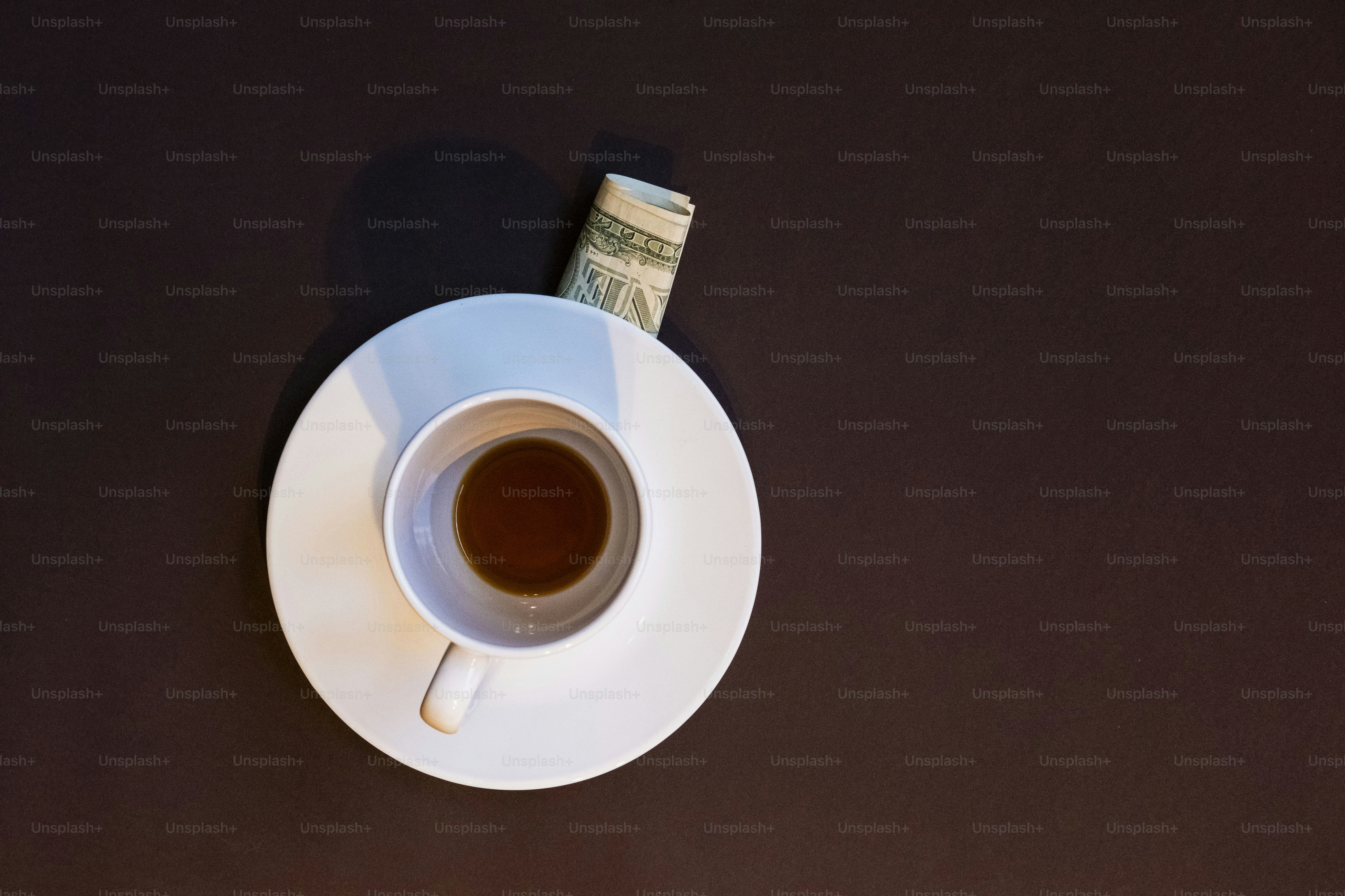 Empty coffee cup, dollar bill on dark surface