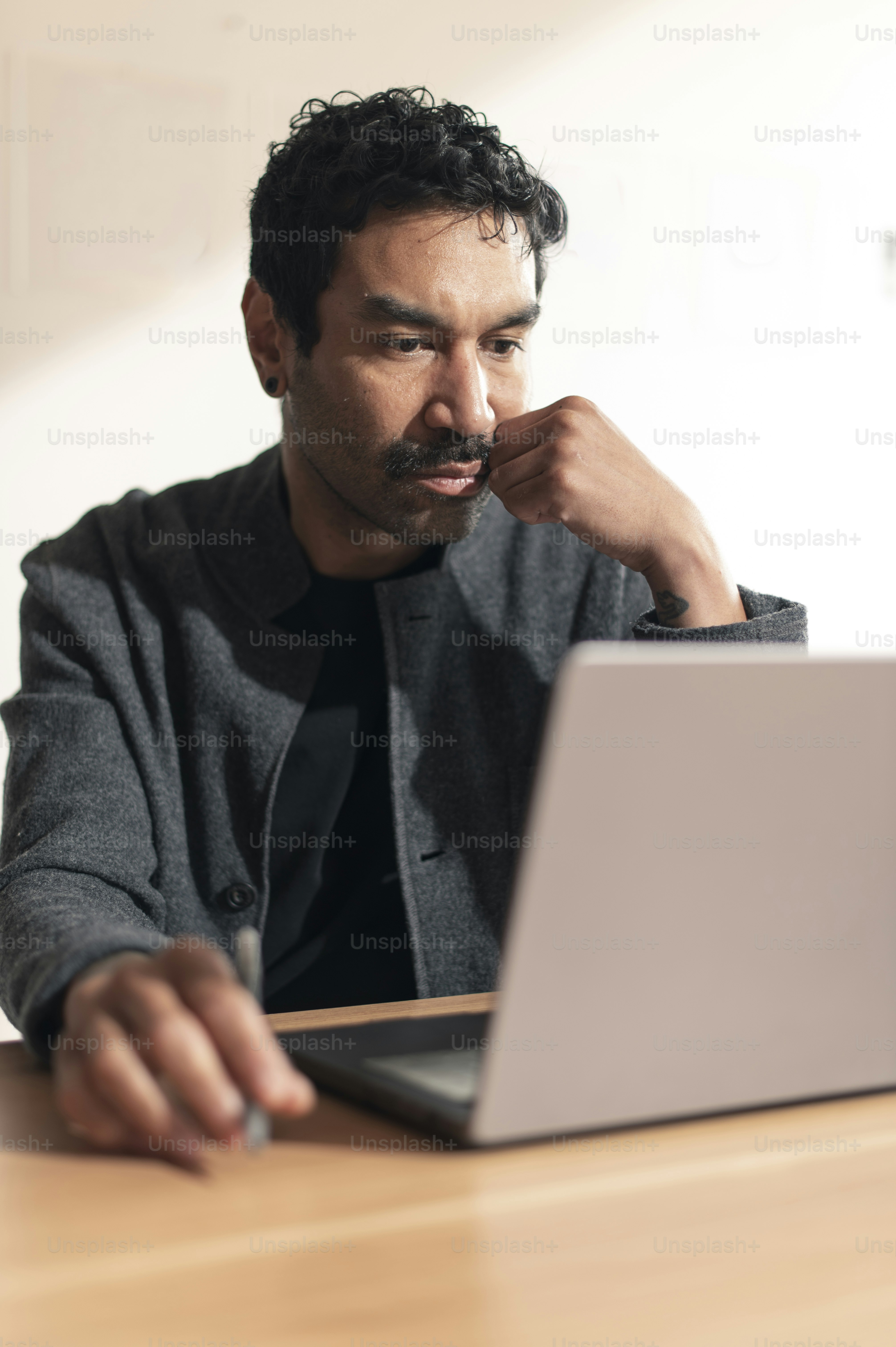 Pria berkumis berkonsentrasi saat bekerja di laptop