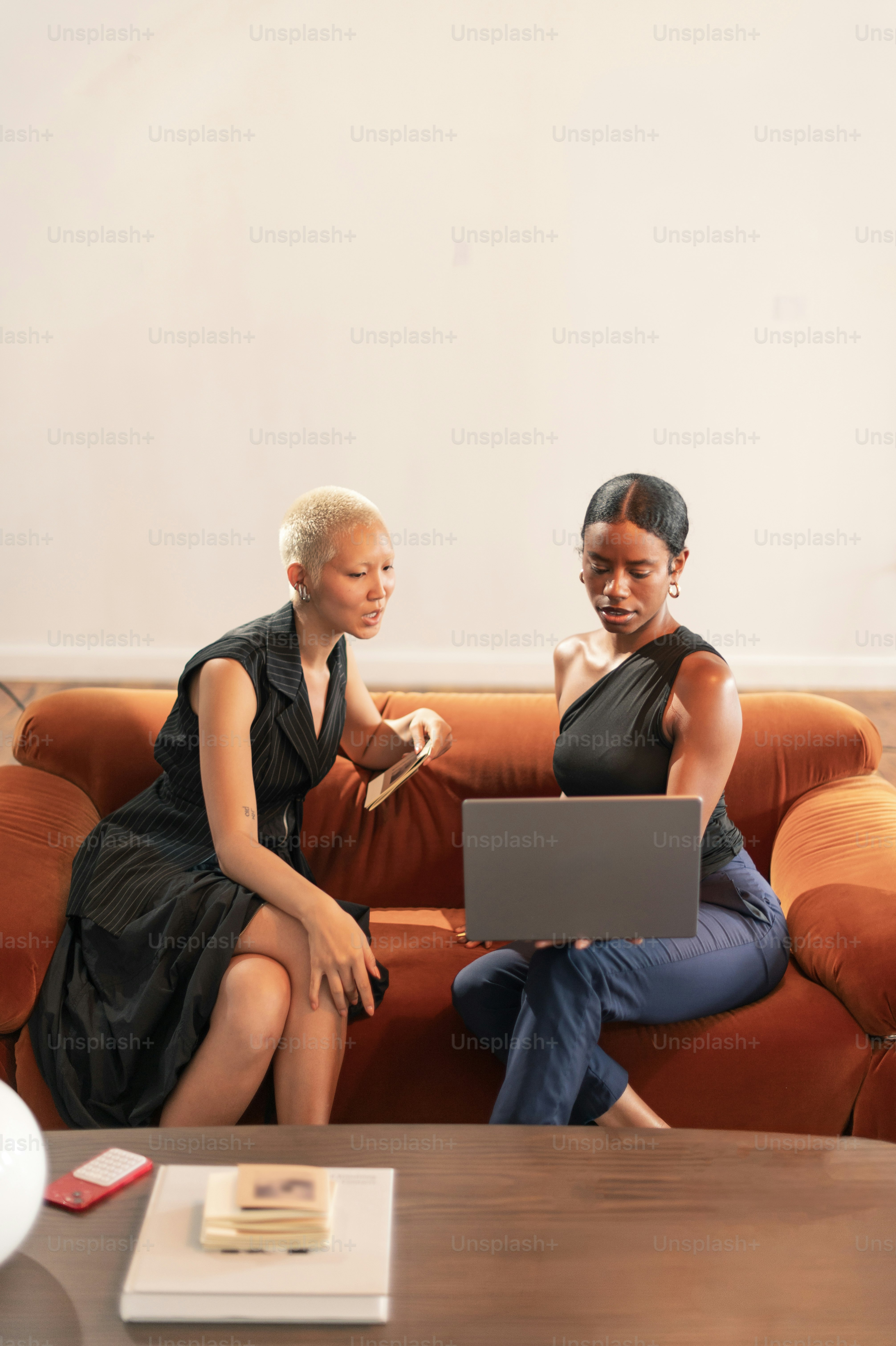 Wanita di sofa oranye melihat laptop