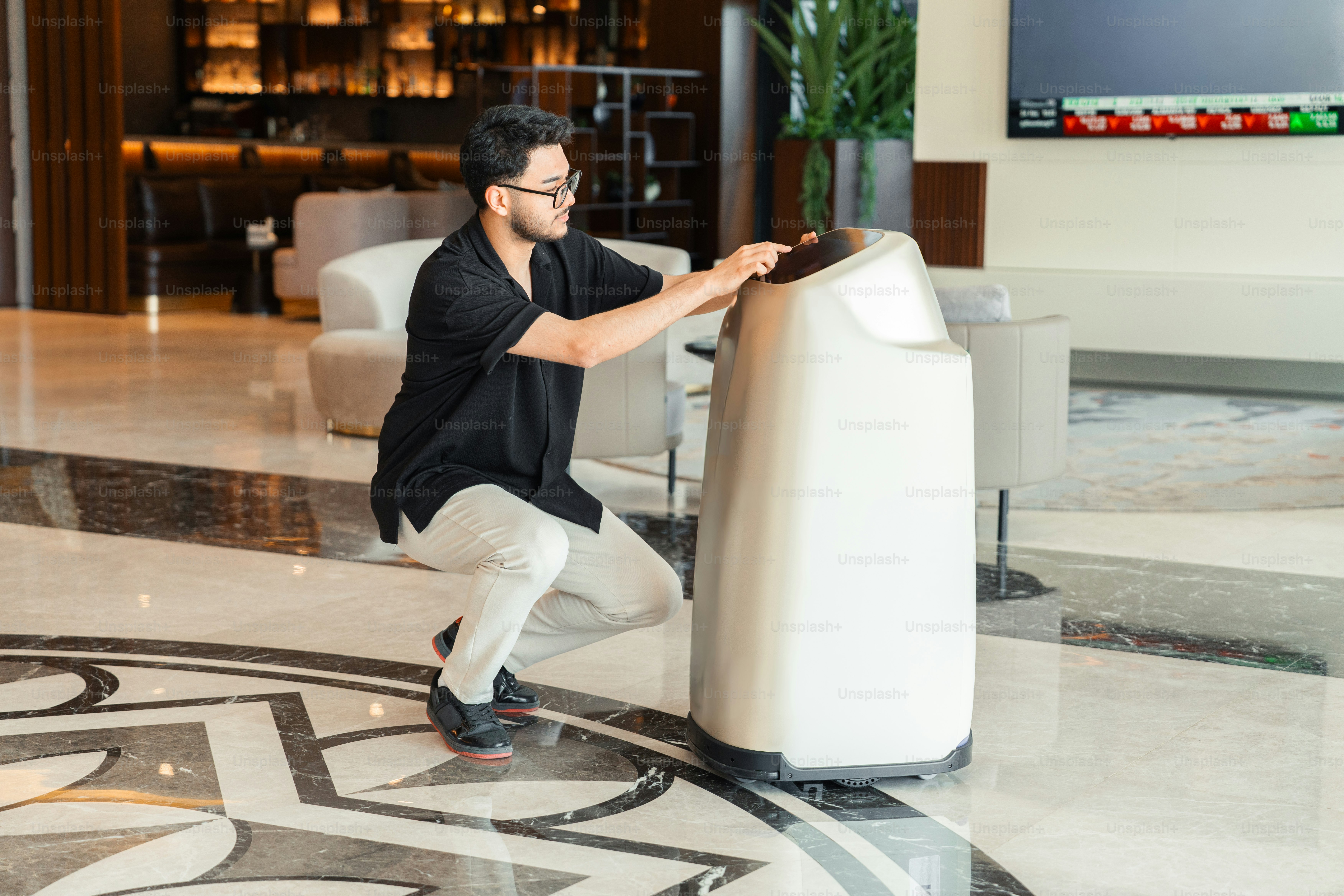 Pria berjongkok untuk berinteraksi dengan robot