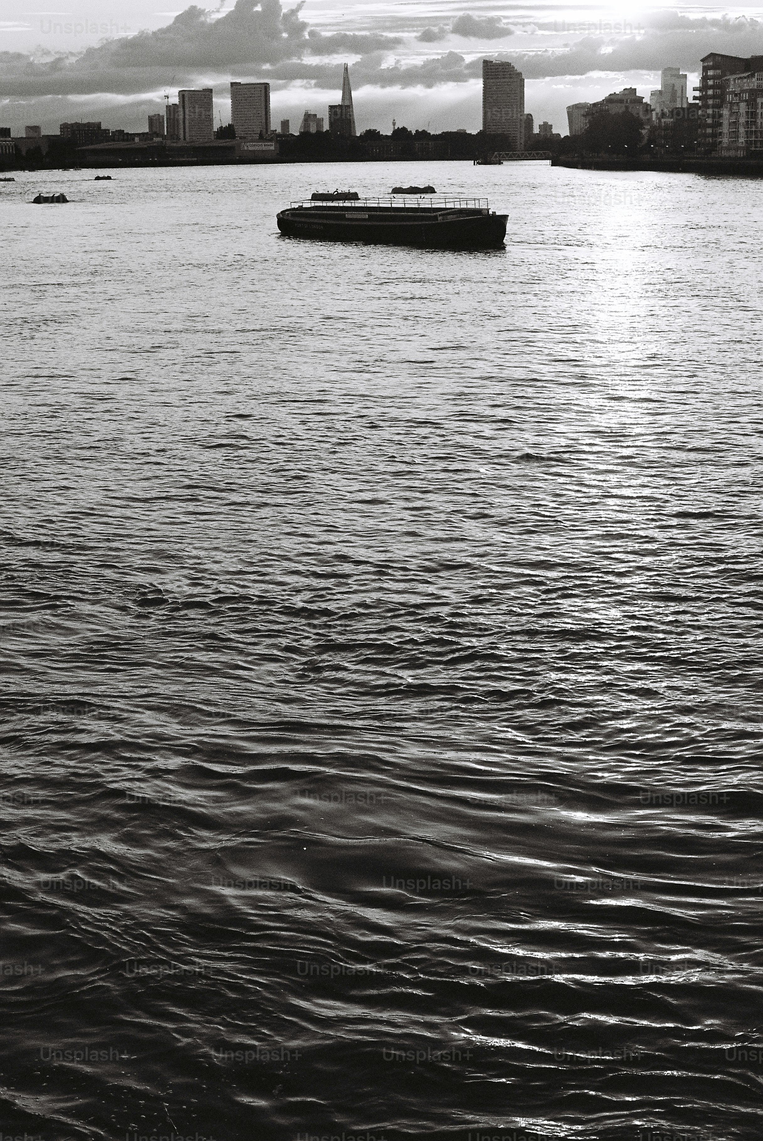 Monochrome river with boat and distant city skyline