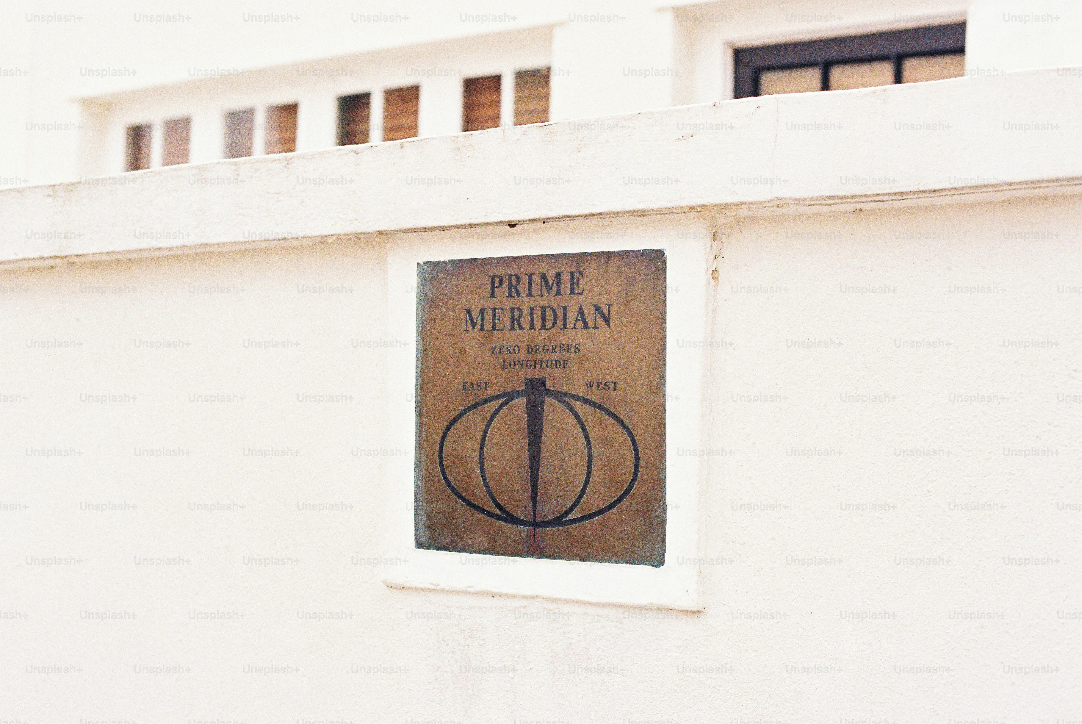 Prime meridian plaque on white building