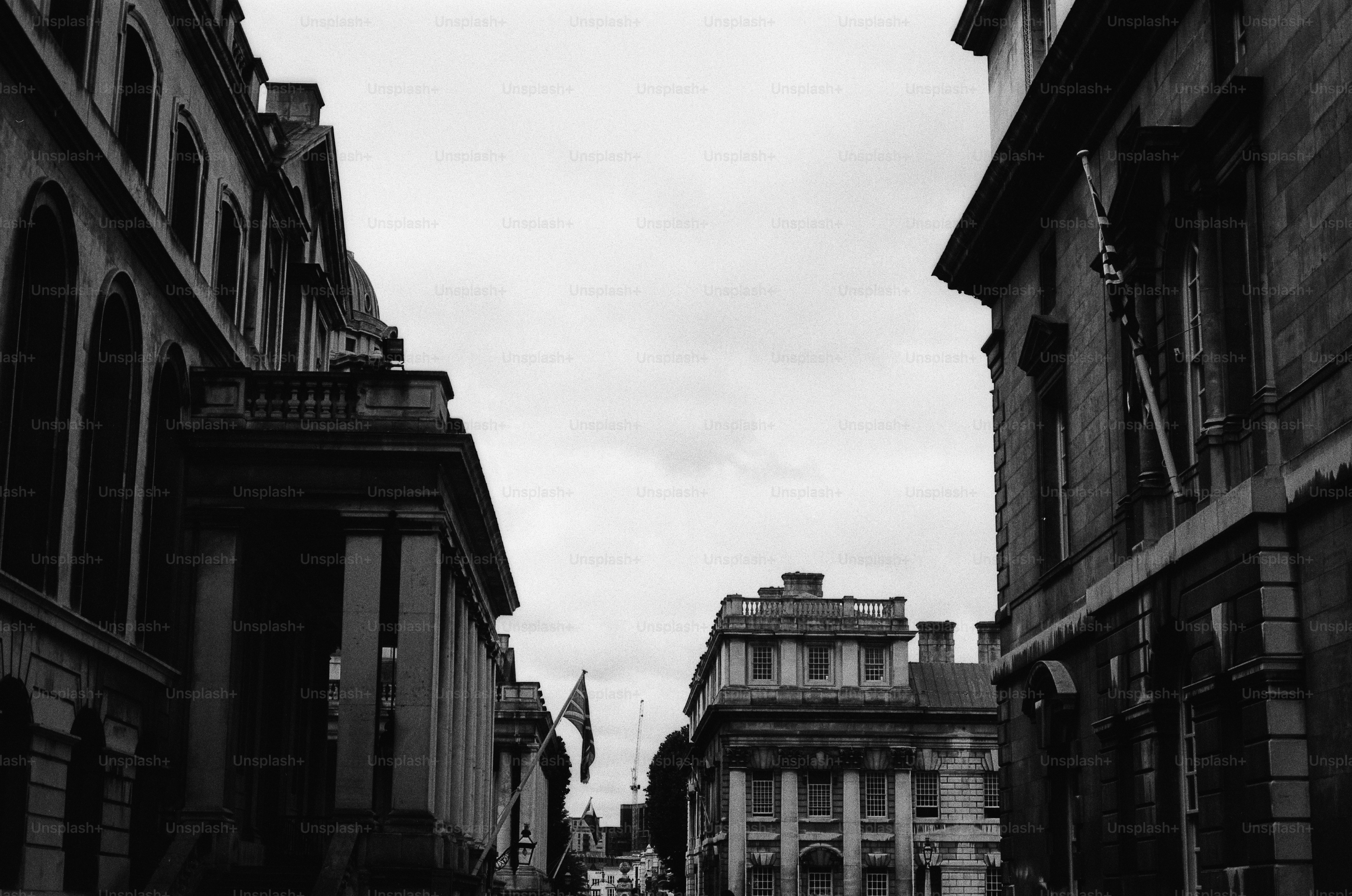 Historic buildings line a street, black and white