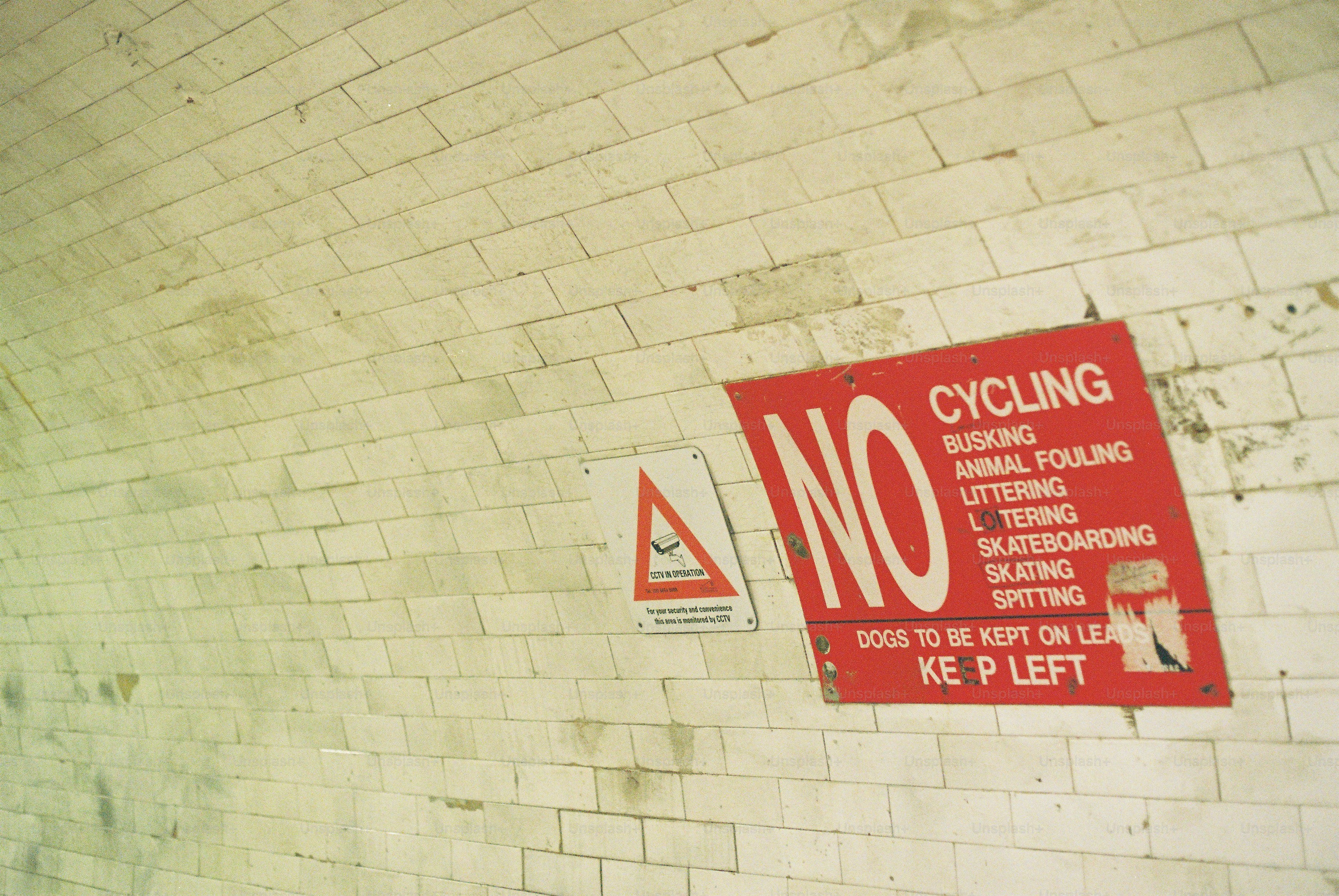Red 'no cycling' sign on white tiled tunnel wall