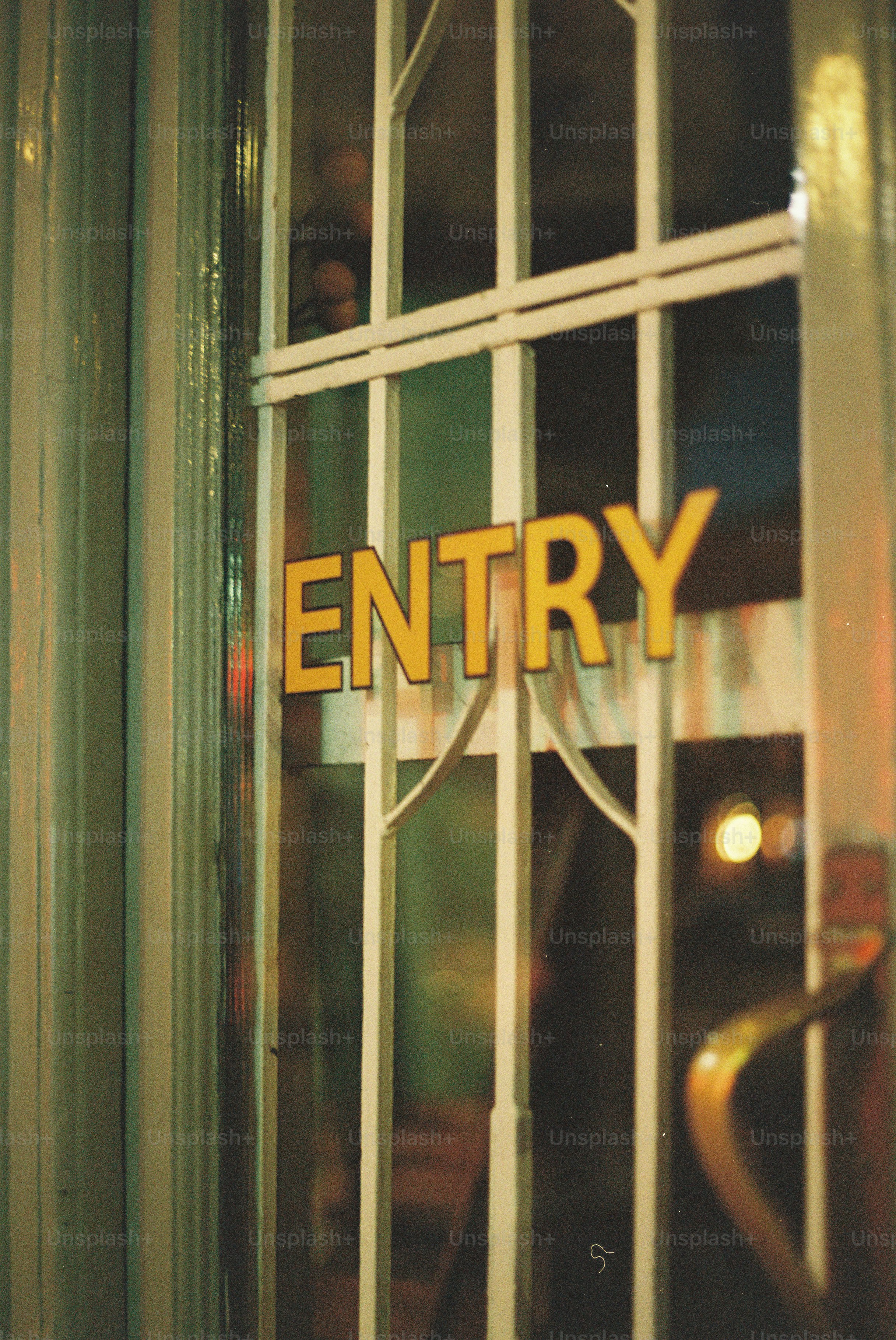 Yellow 'entry' sign on a gridded glass door