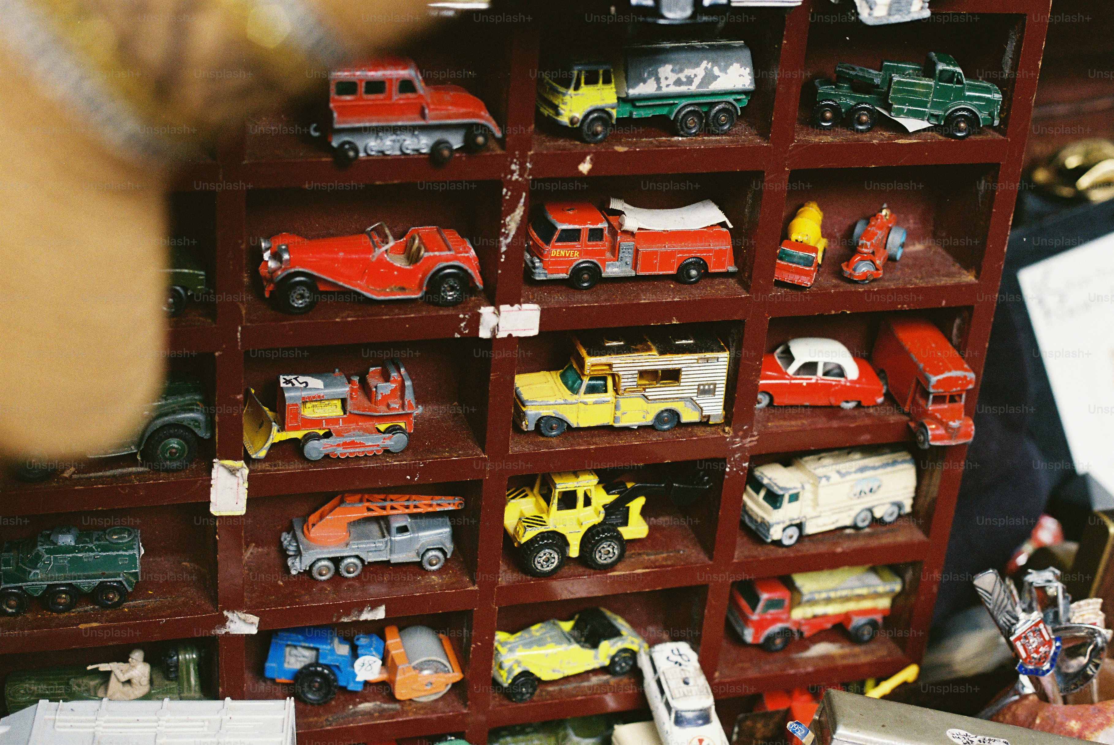 Miniature toy cars and trucks displayed in wooden shelf