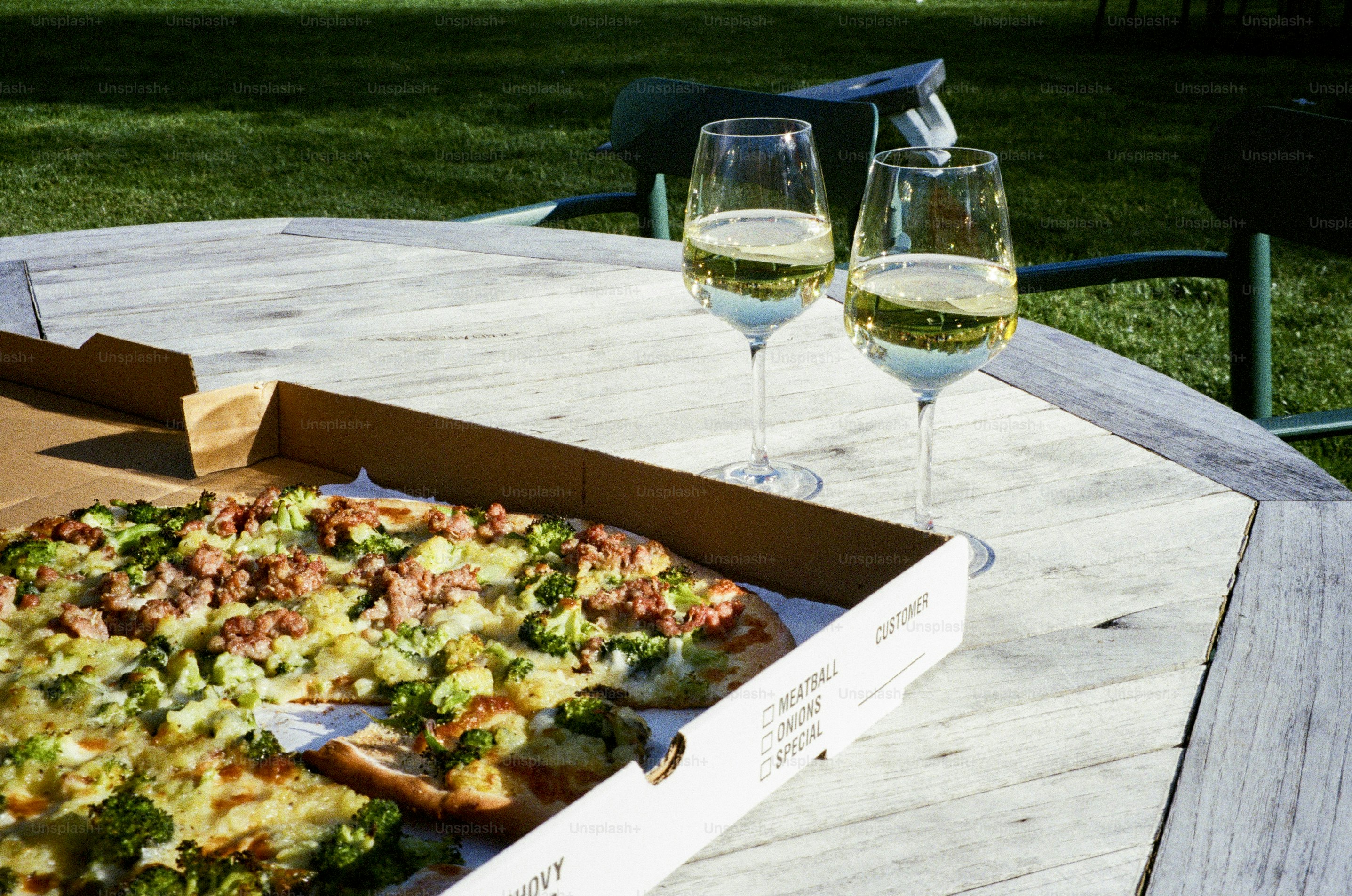 Pizza e vinho branco em uma mesa de madeira externa