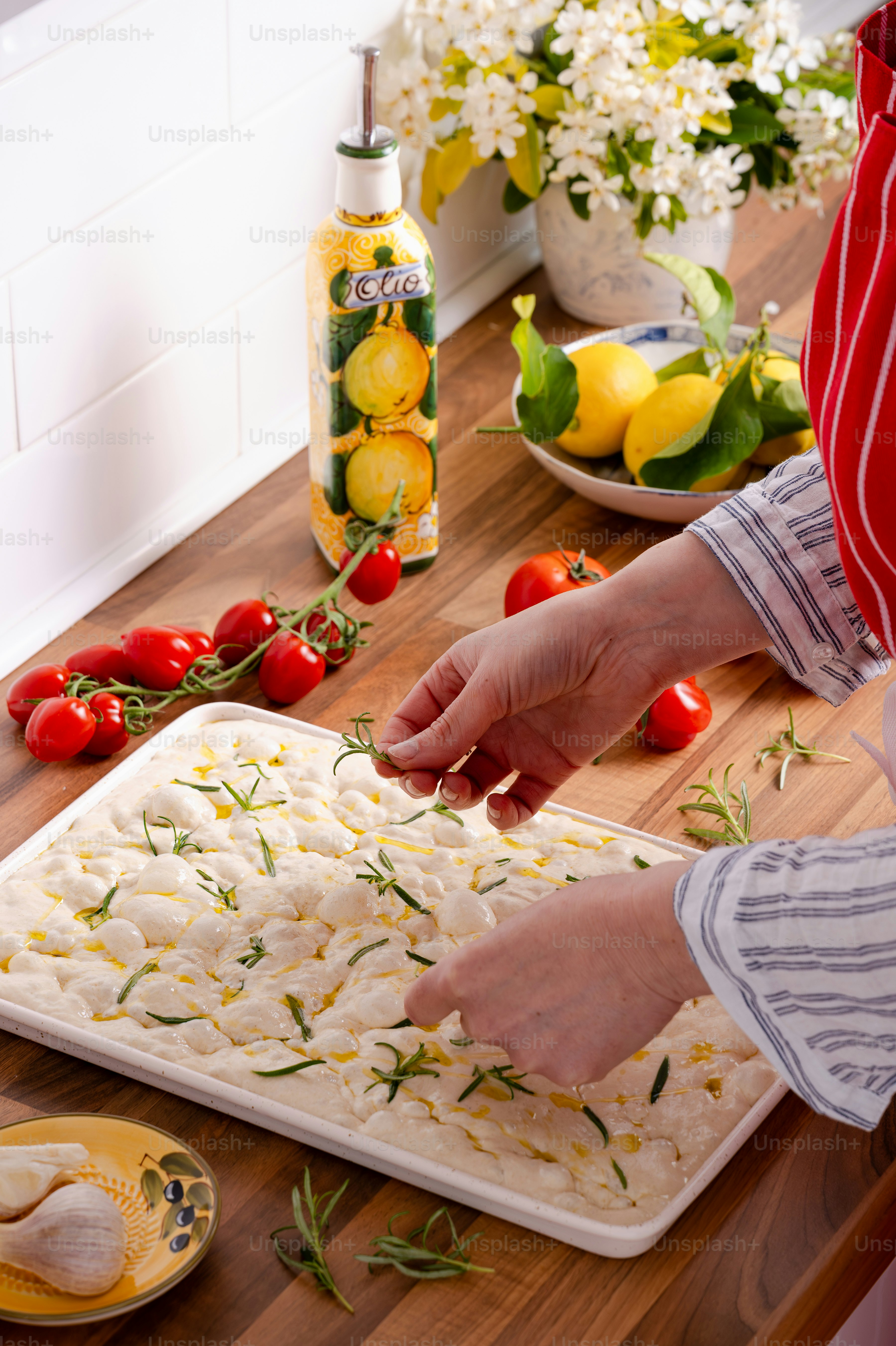 Preparing focaccia dough with fresh rosemary and cherry tomatoes