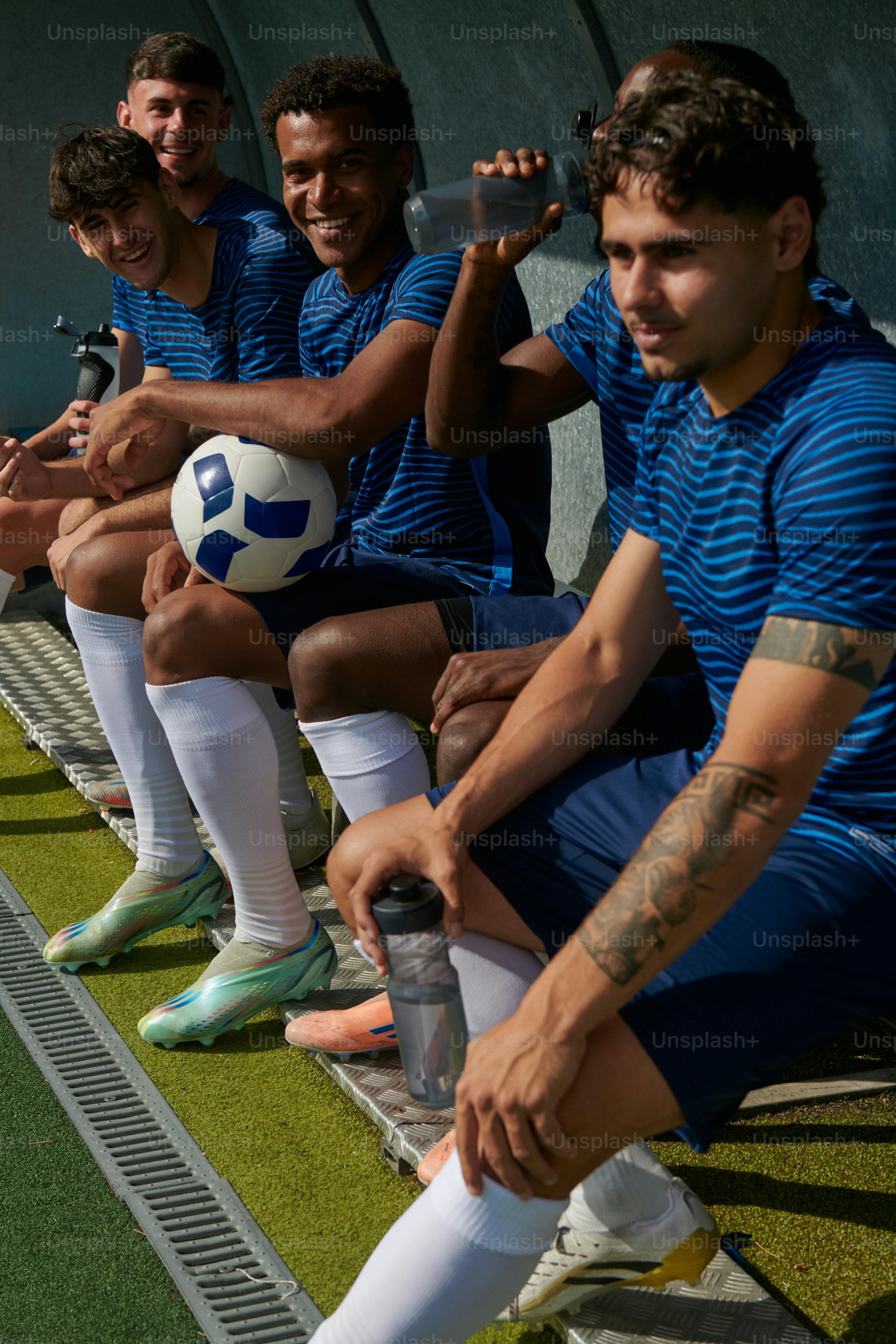 Fußballspieler, die sich auf der Bank mit Ball und Flaschen ausruhen