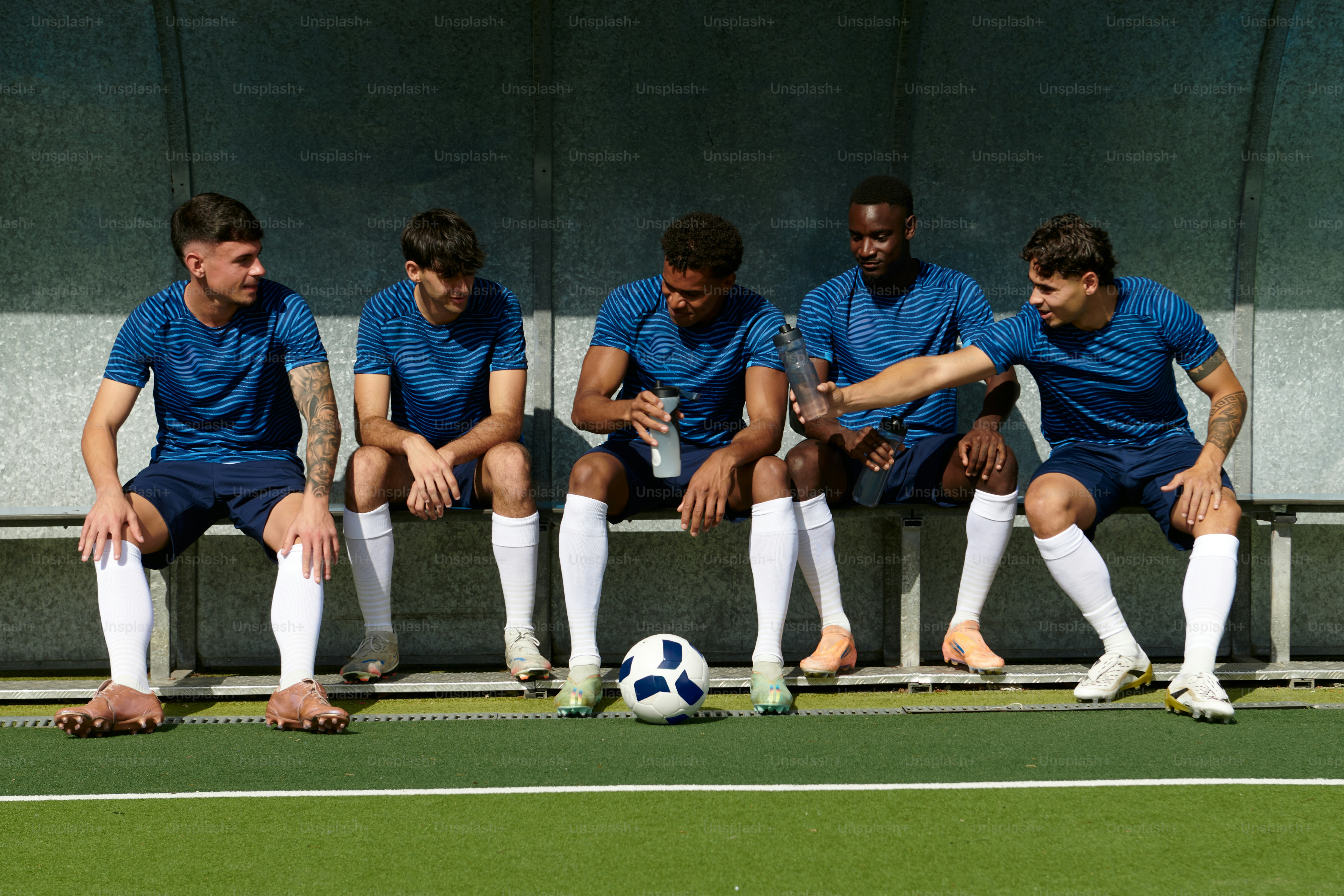 Five soccer players resting on a dugout bench photo – Football Image on ...