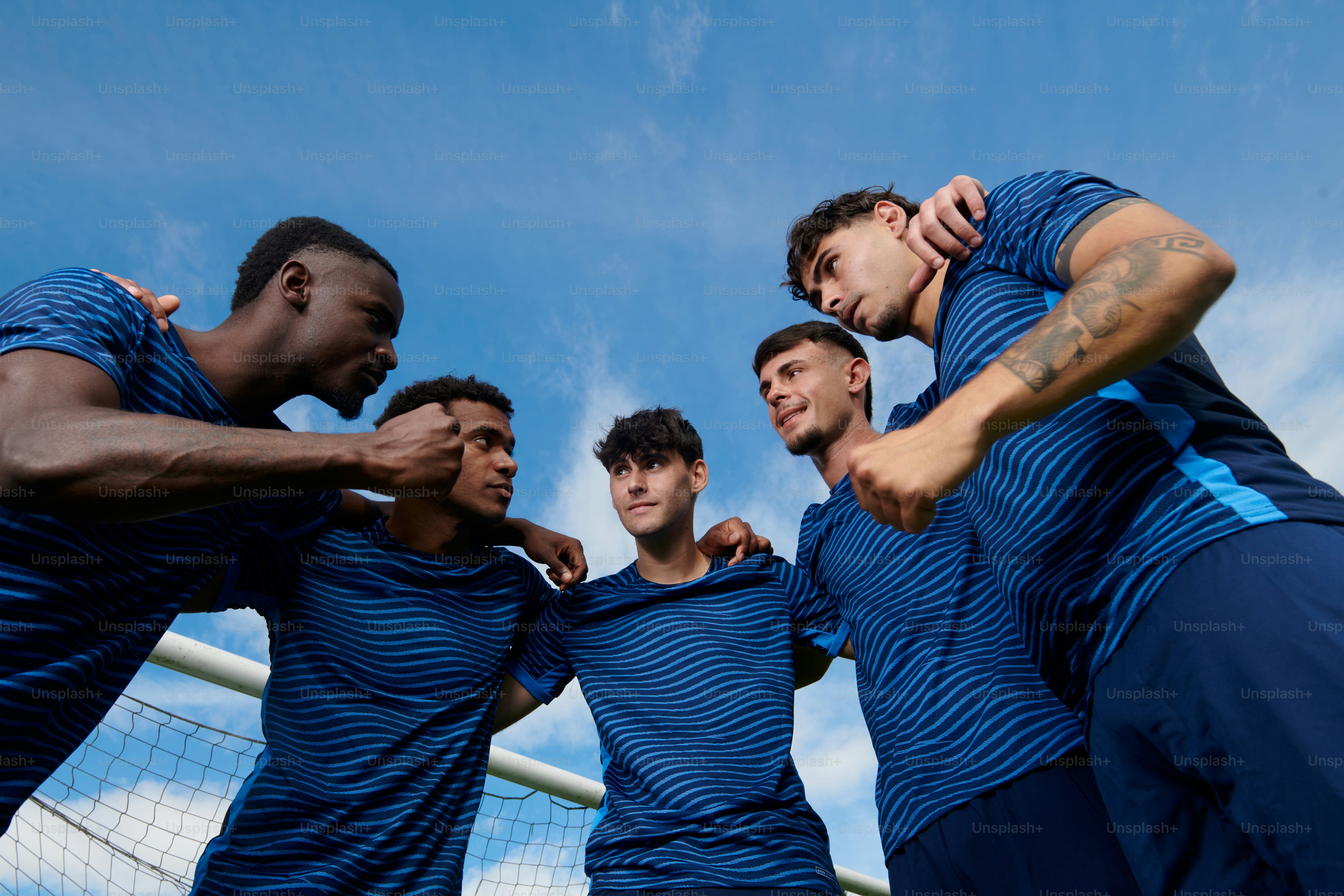 Männliche Fußballspieler drängen sich in blauen Trikots zusammen
