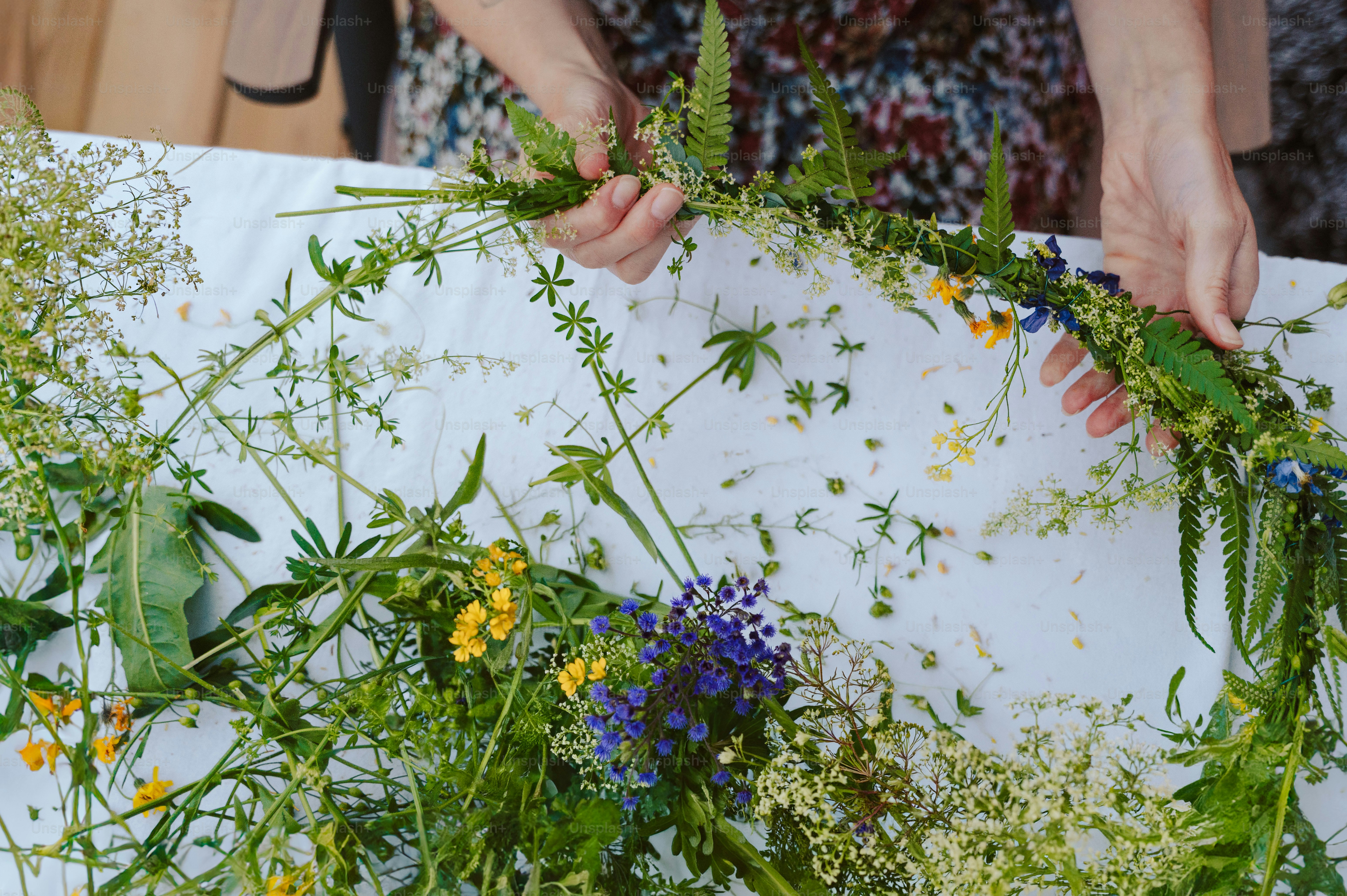 Hands making a midsummer flower crown with wildflowers
