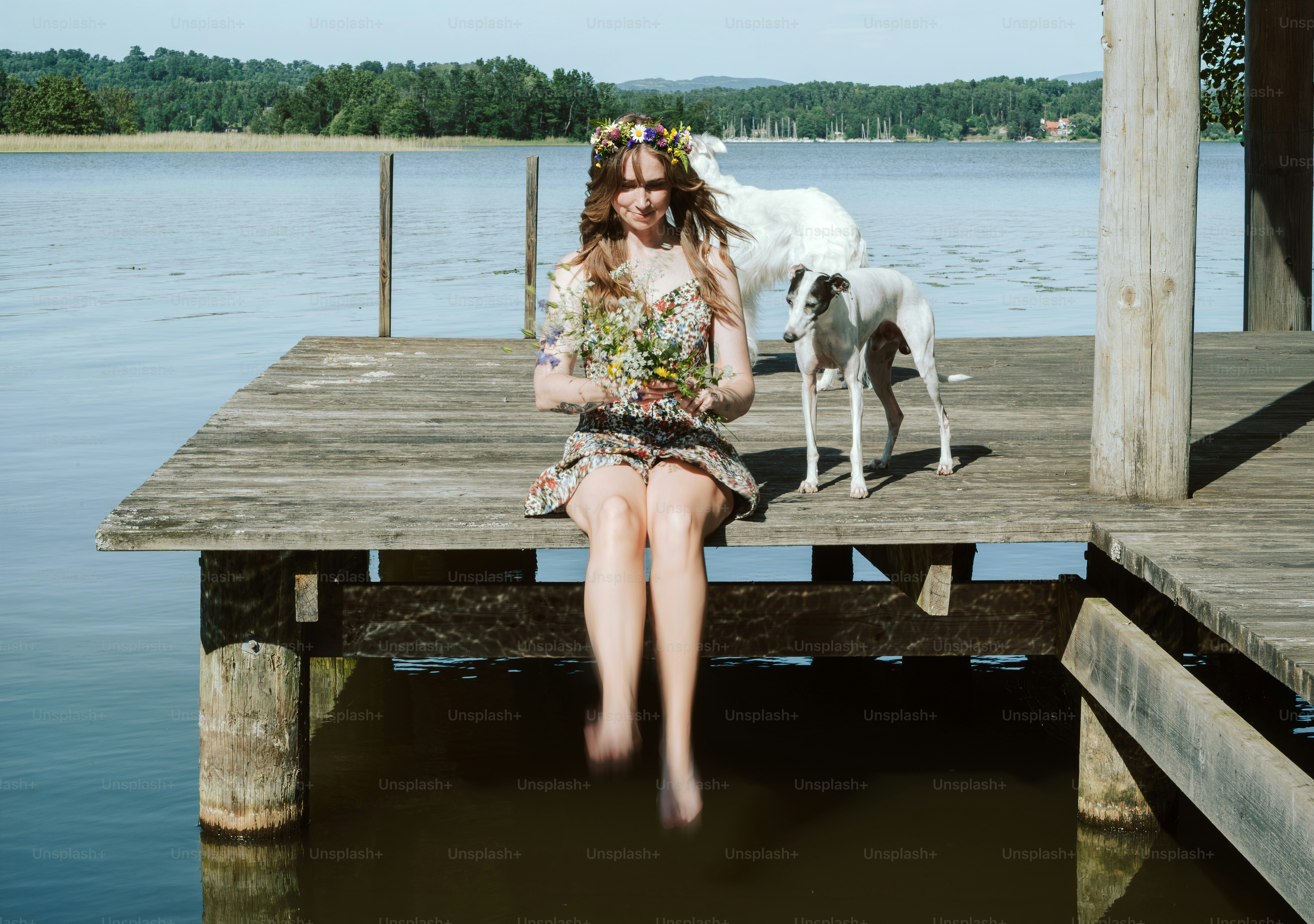 Woman with flower crown, dogs on lake dock