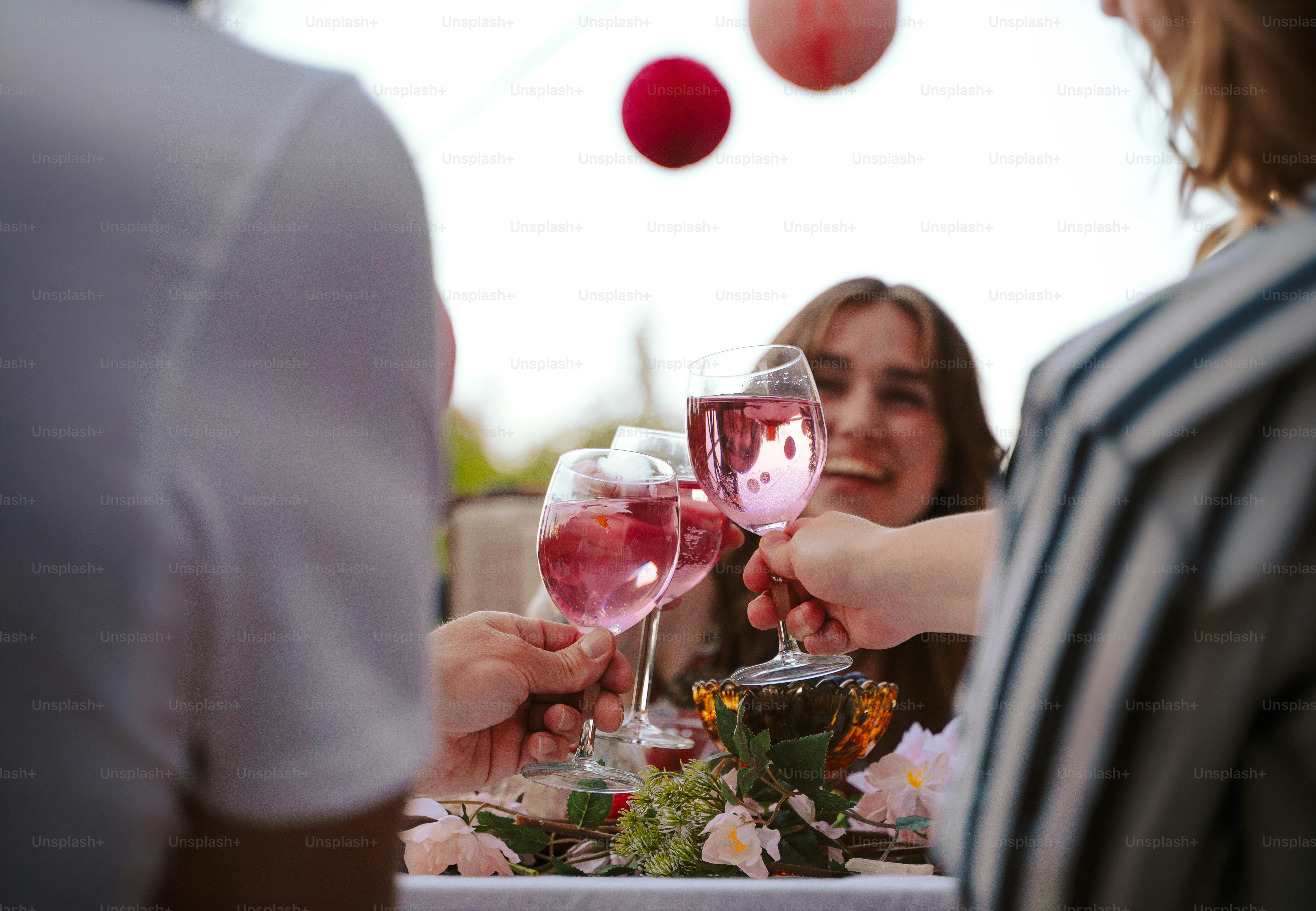 Friends toasting pink drinks with festive outdoor decorations