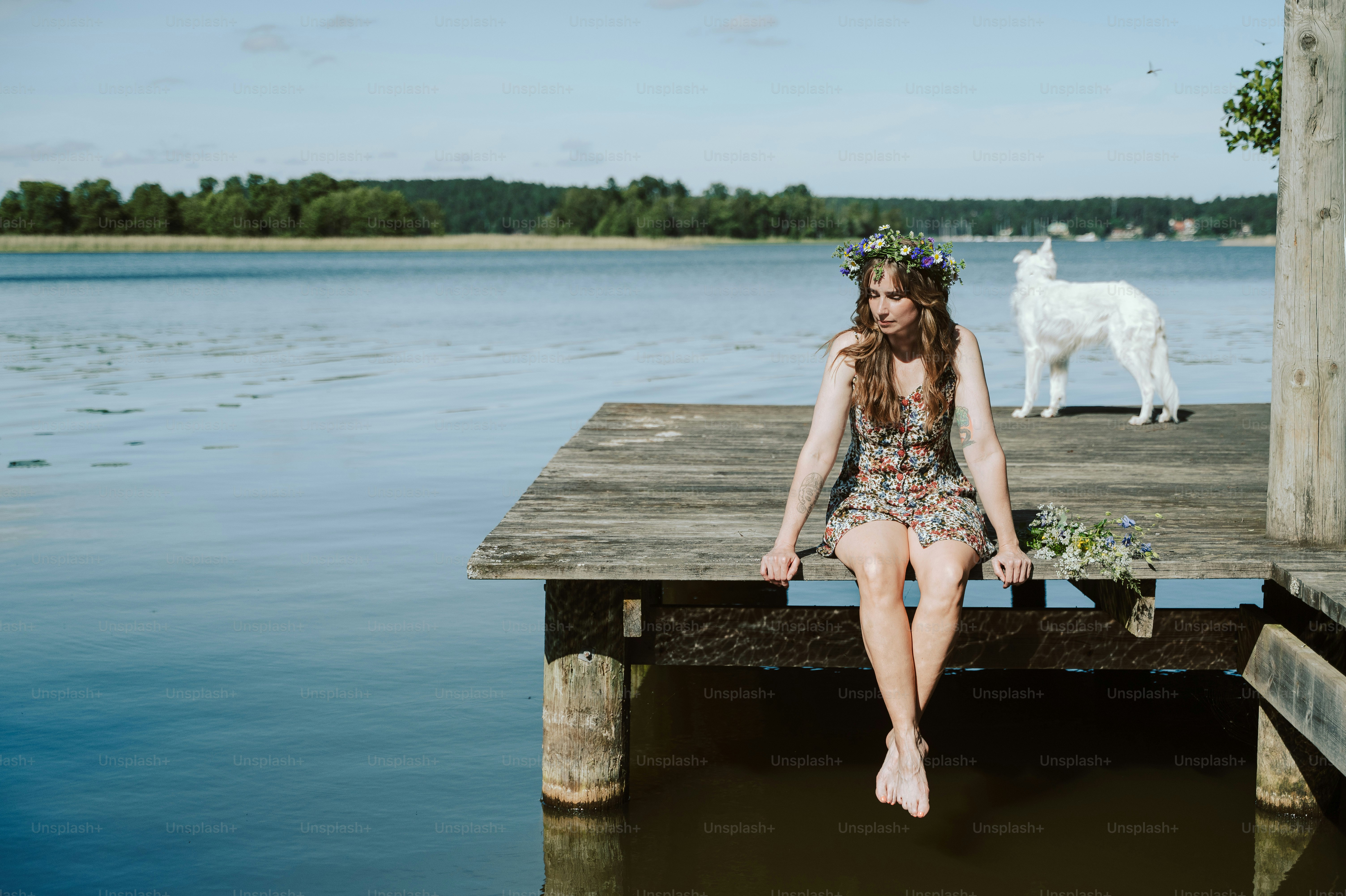 Woman with flower crown, dog on lake dock