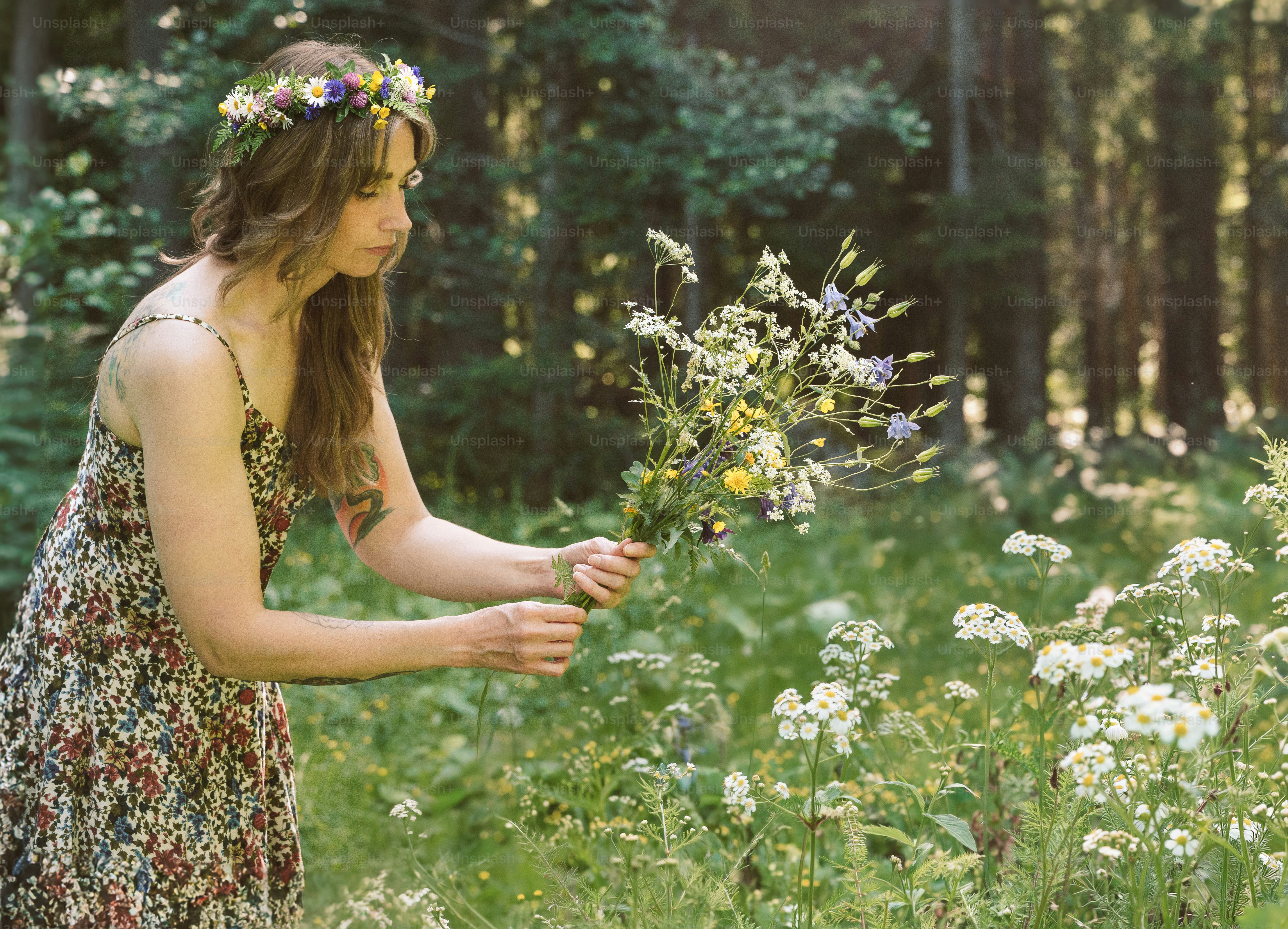 Frau mit Blumenkranz sammelt Wildblumen im Wald