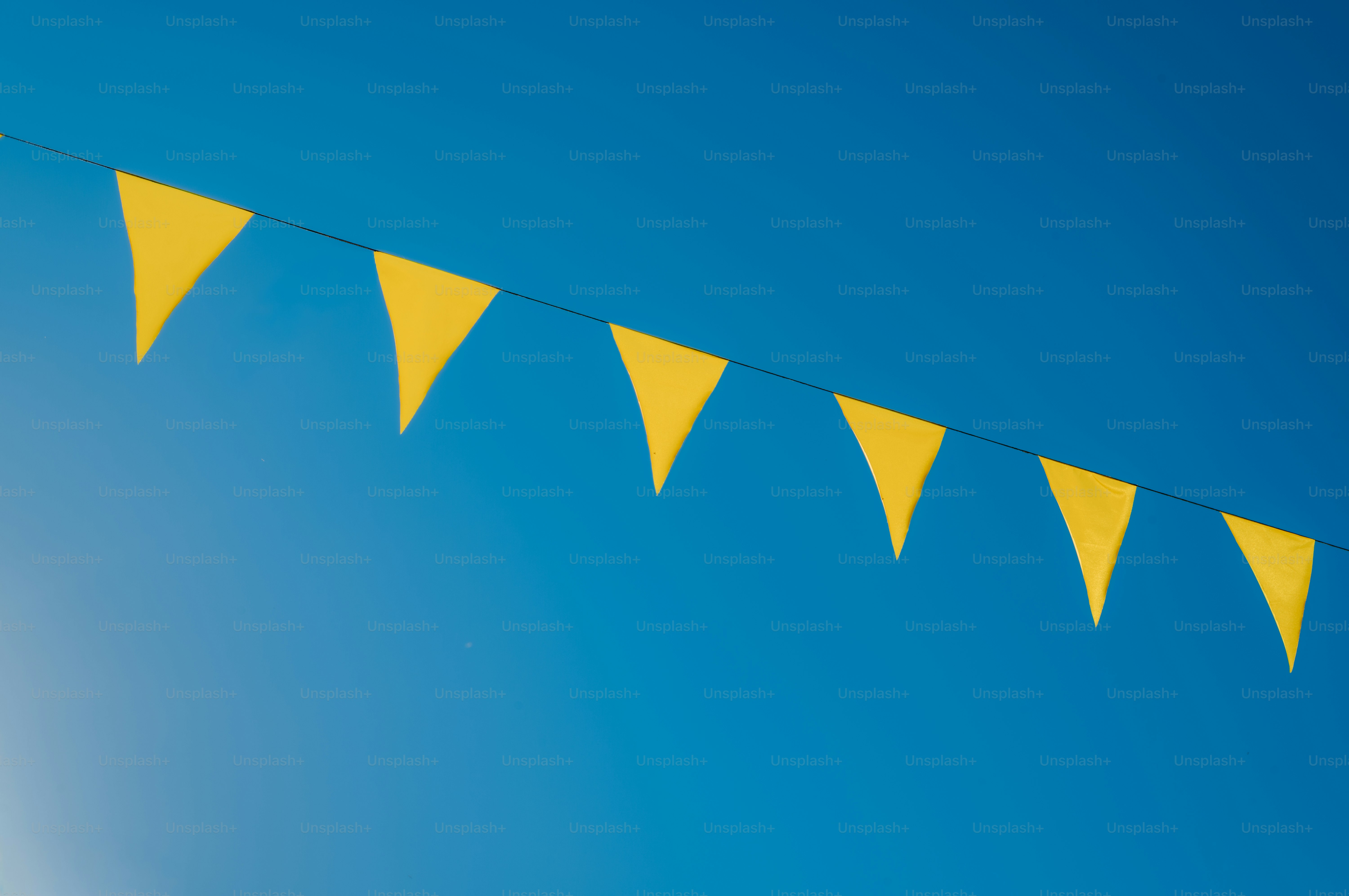 Yellow triangular flags against a clear blue sky