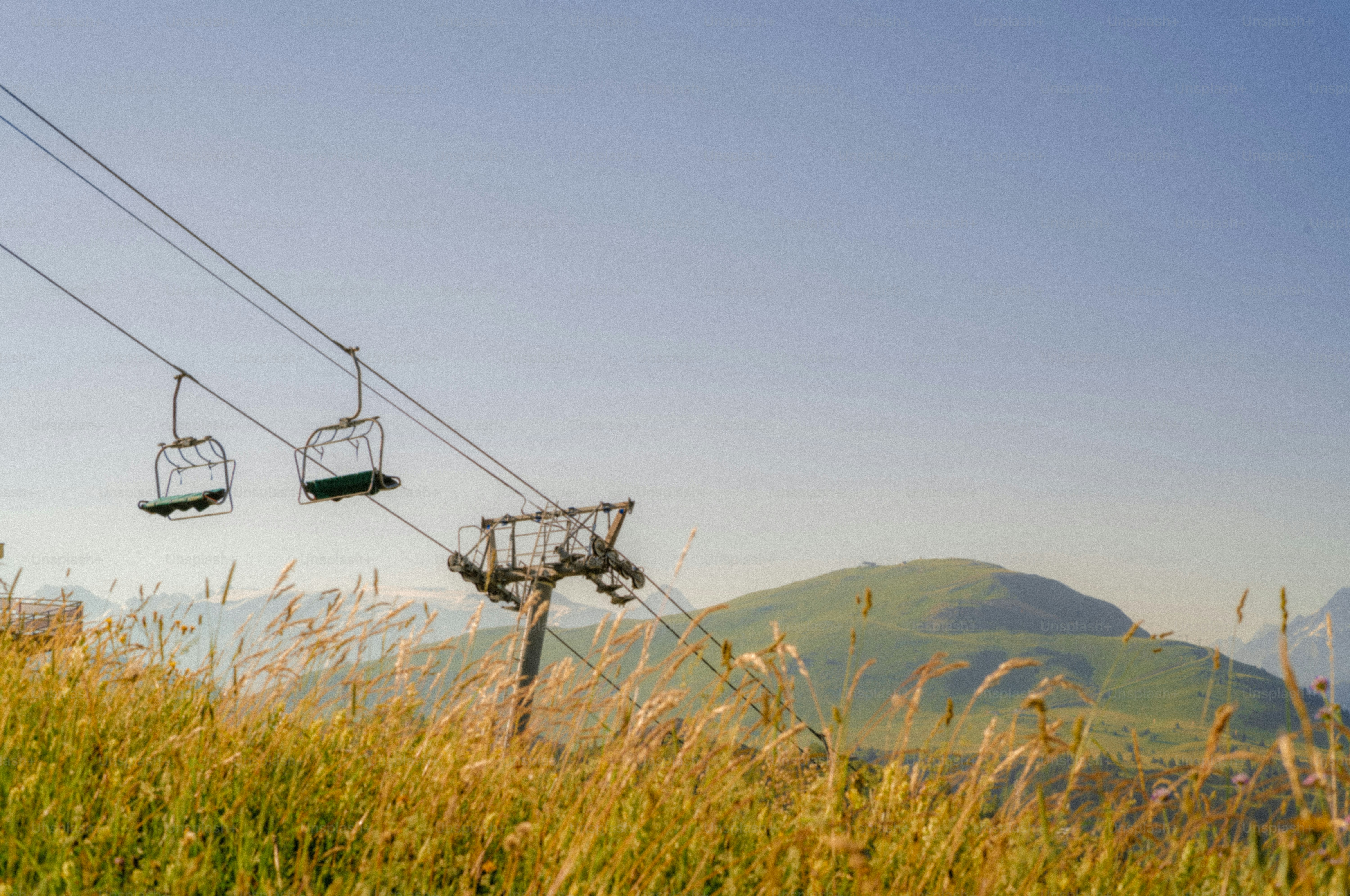 Empty ski lift chairs over grassy mountain landscape