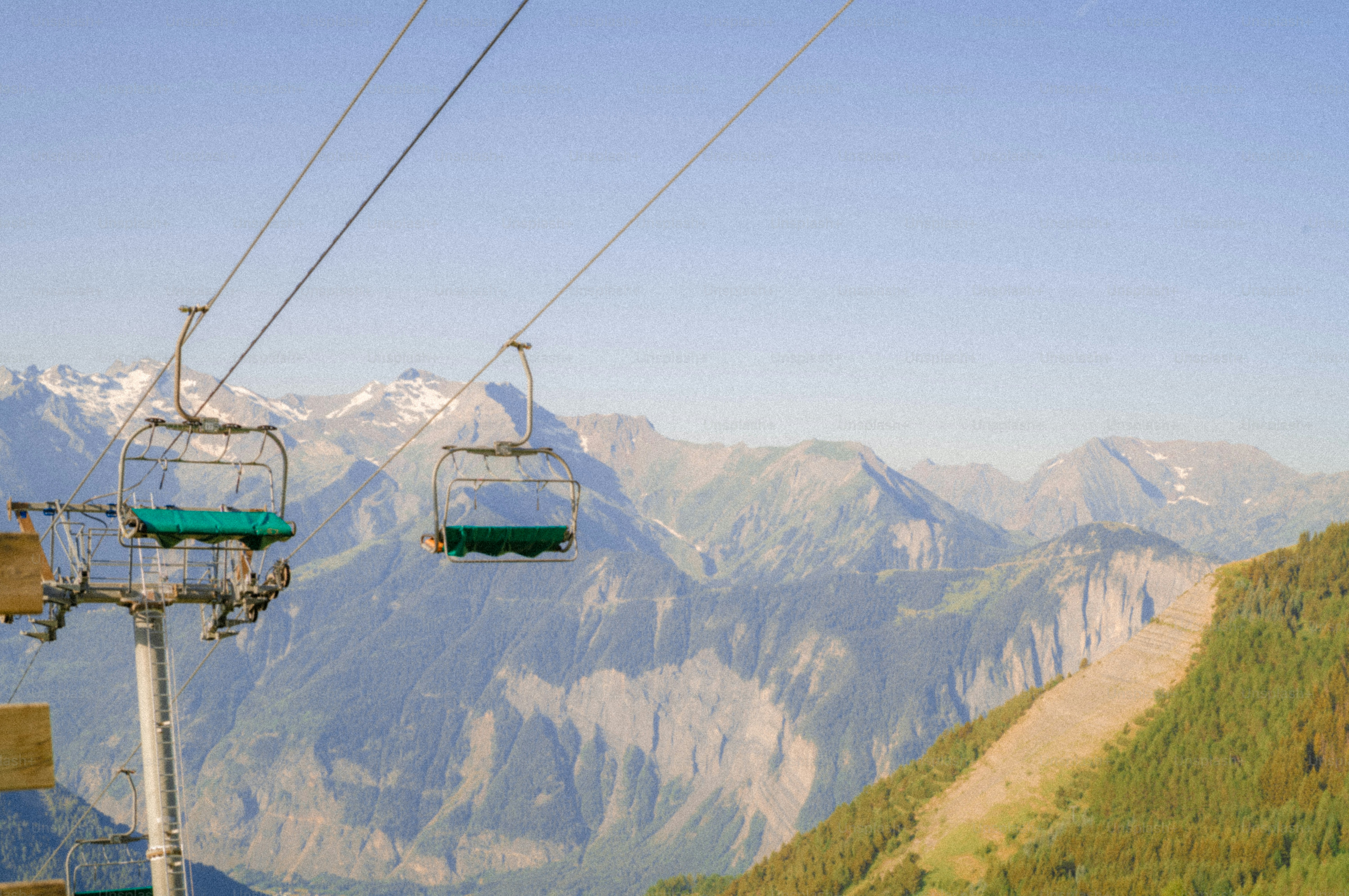 Empty chairlifts ascending a green mountain landscape